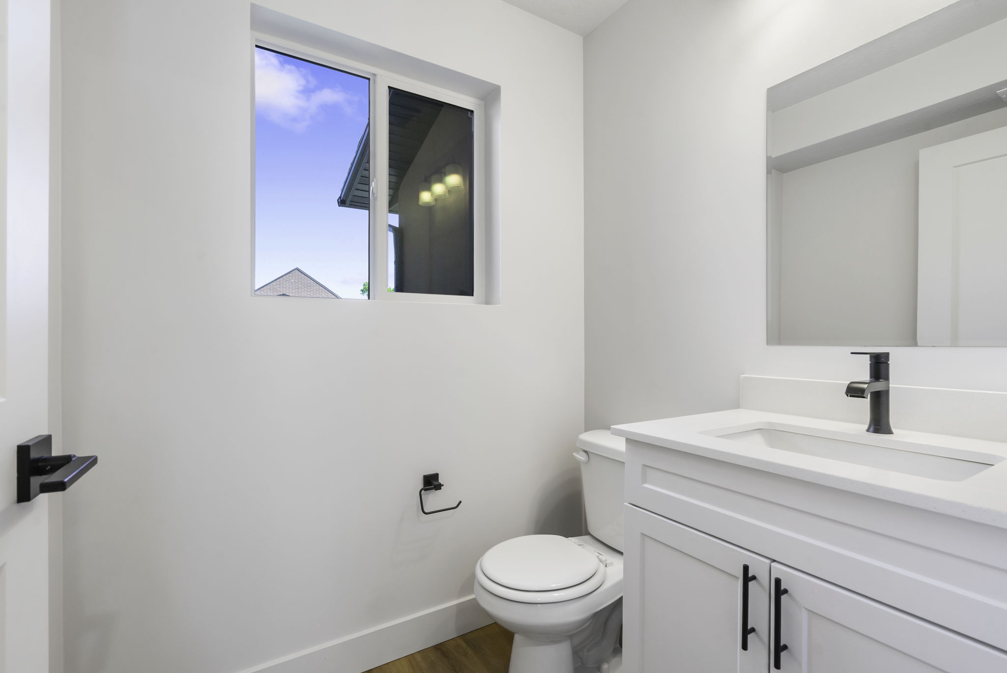 White vanity with a single basin sink, matte black faucet, and coordinating hardware