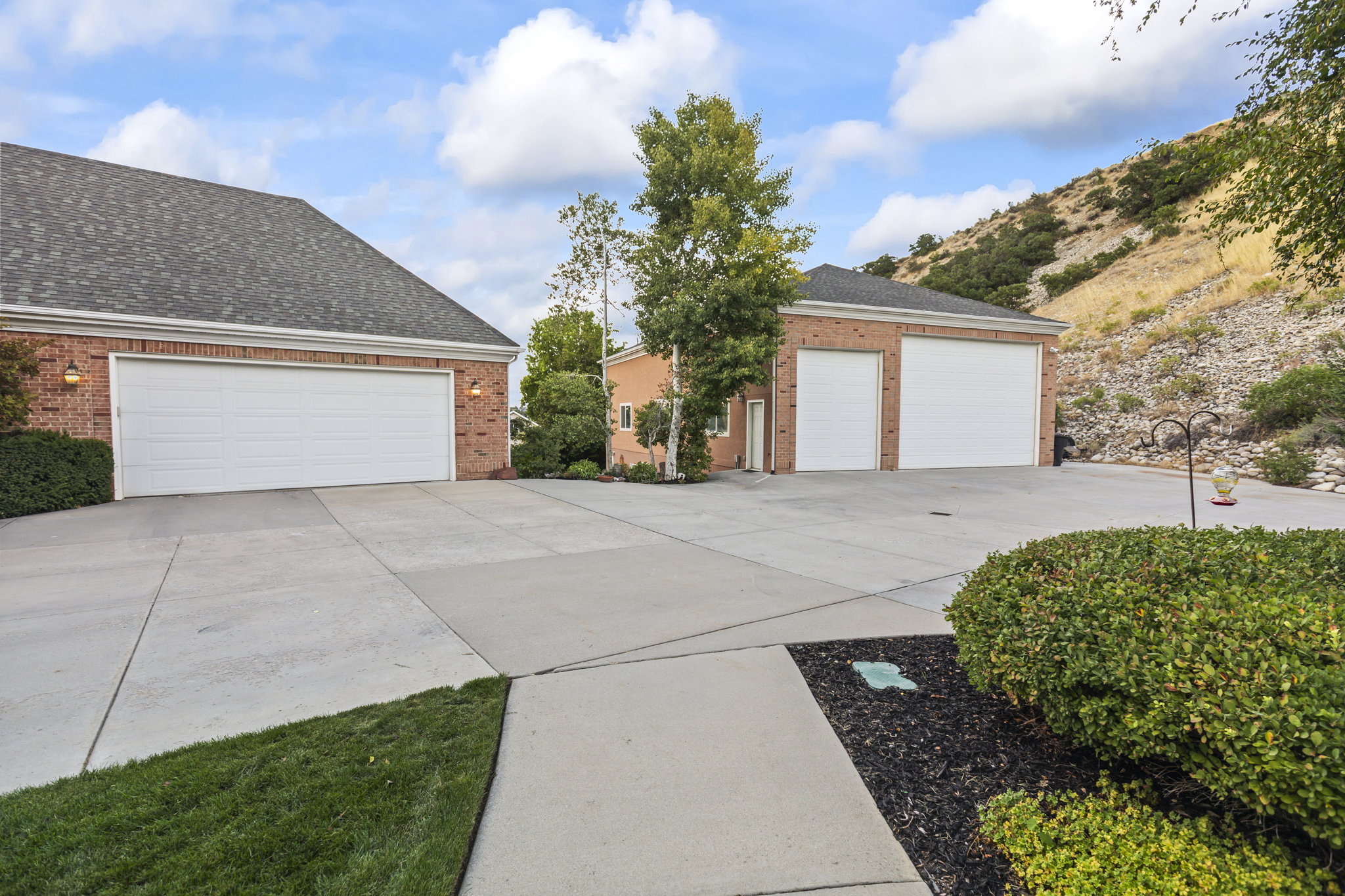 View of front of house featuring brick siding, a garage, a shingled roof, and an outdoor structure