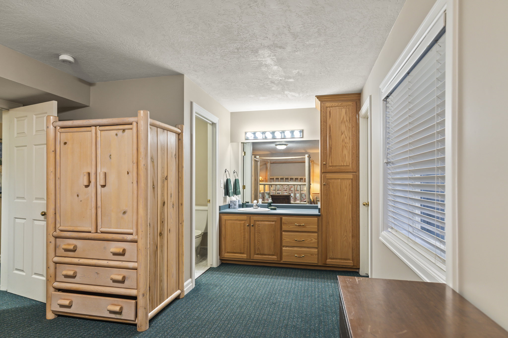 Full bath with a closet, vanity, a textured ceiling, and dark carpet