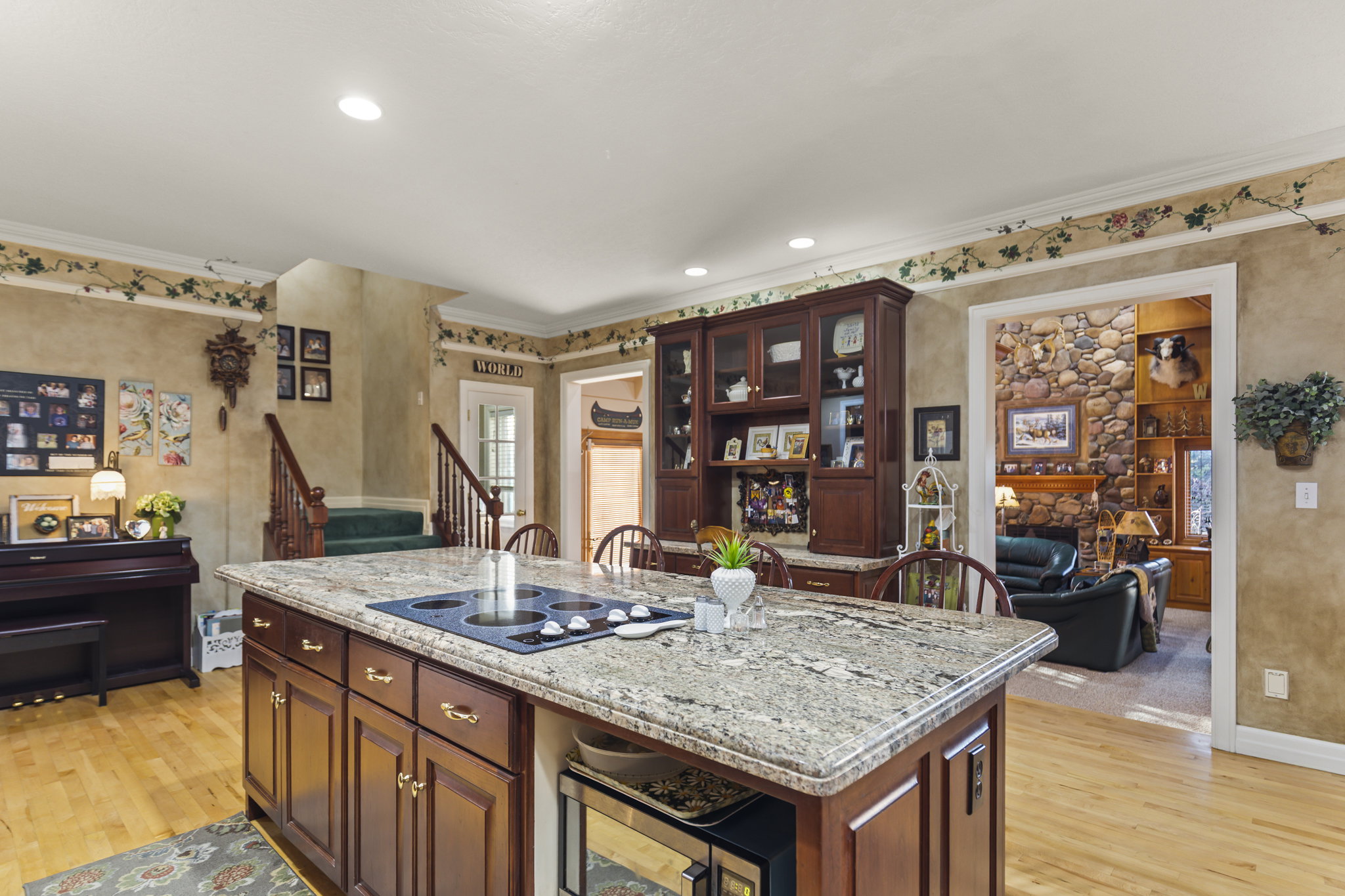 Kitchen featuring light wood-style flooring, light stone countertops, crown molding, beverage cooler, and a kitchen island