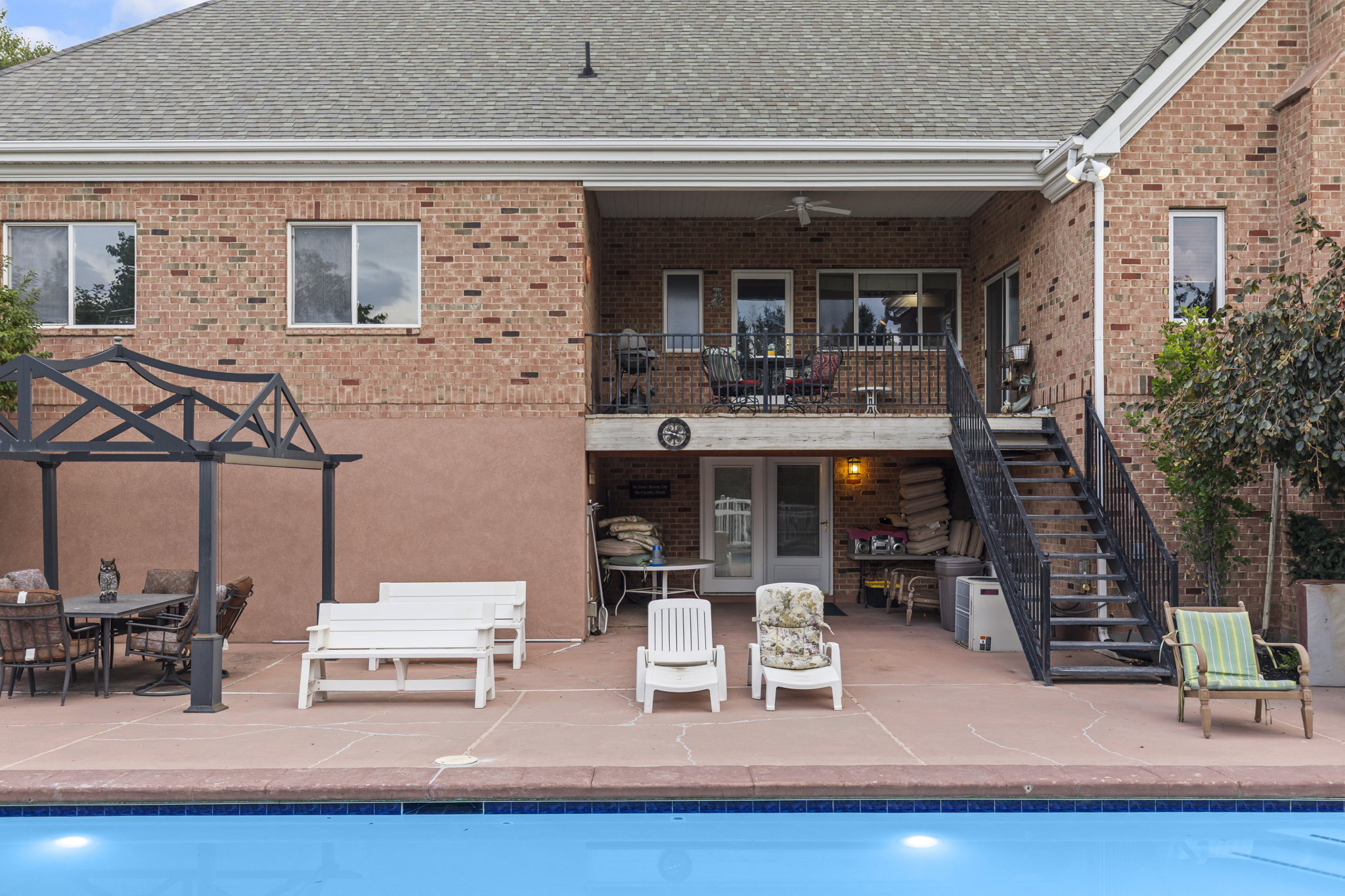 Rear view of property with outdoor dining area, a patio area, brick siding, an outdoor pool, and roof with shingles