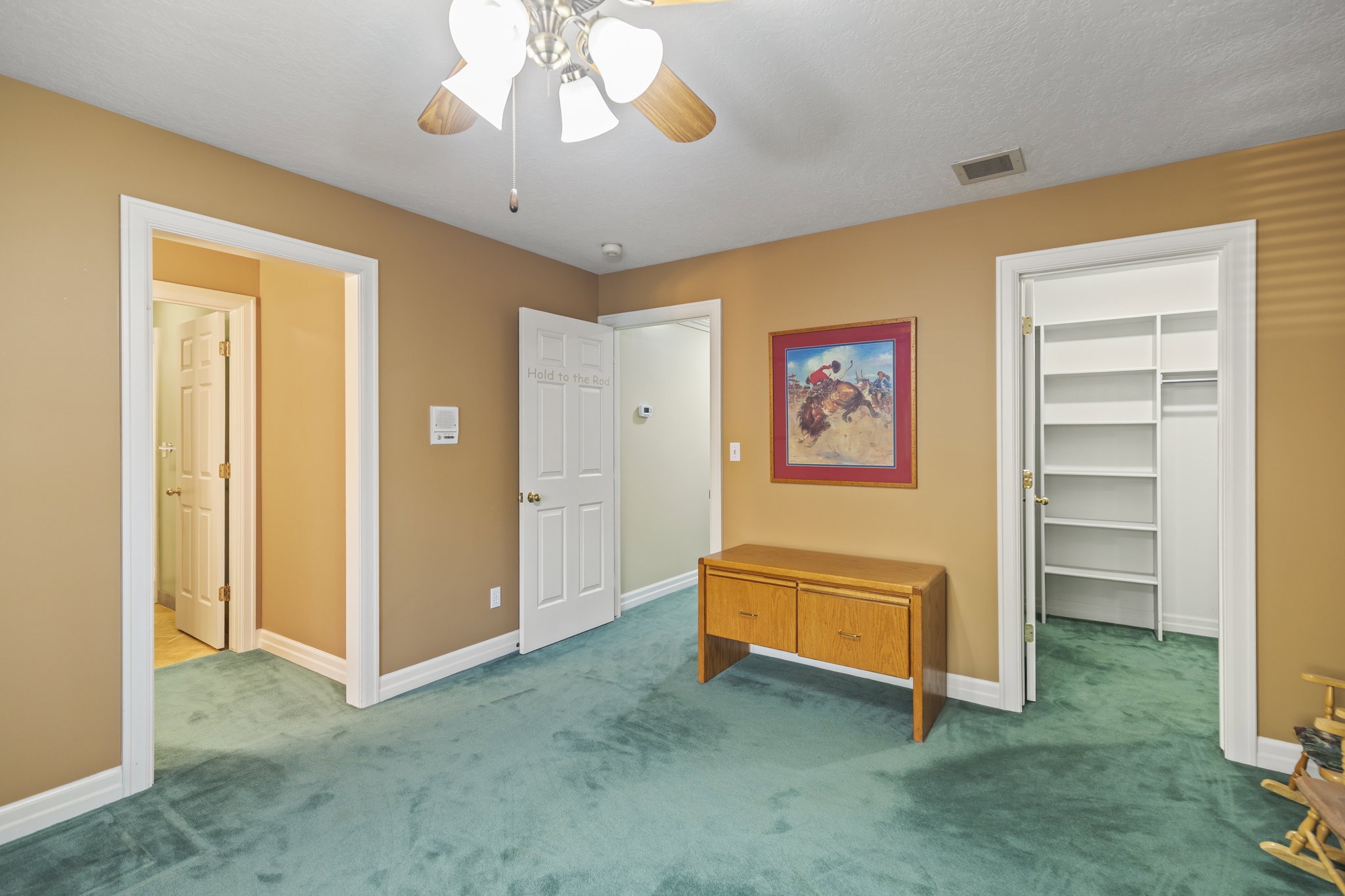 Unfurnished bedroom featuring a walk in closet, carpet floors, and ceiling fan