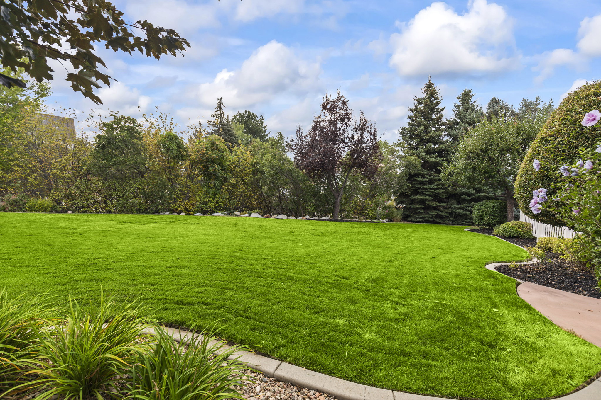 View of green lawn featuring view of scattered trees