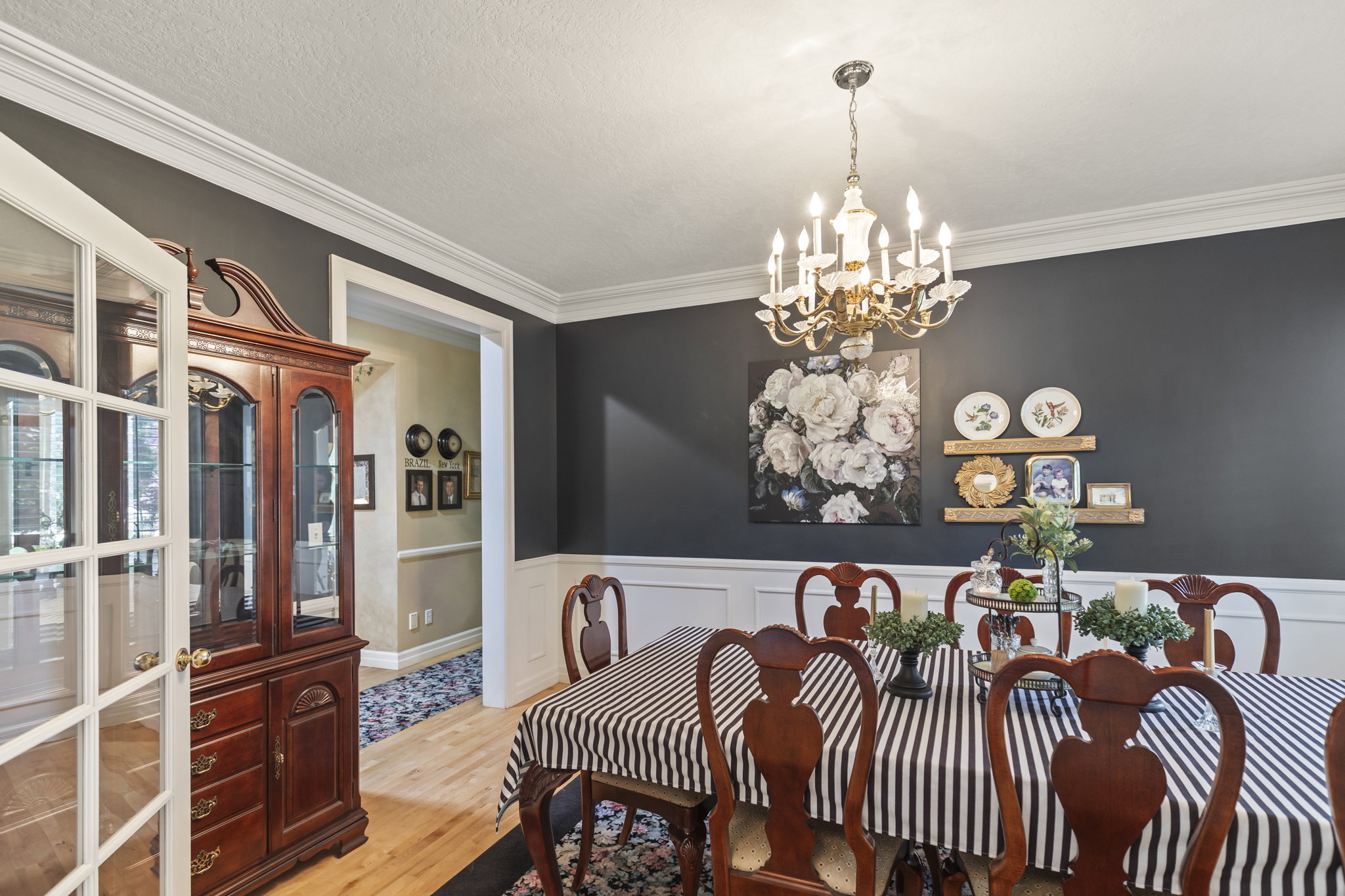 Dining room with ornamental molding, suspended lighting, light wood finished floors, and wainscoting