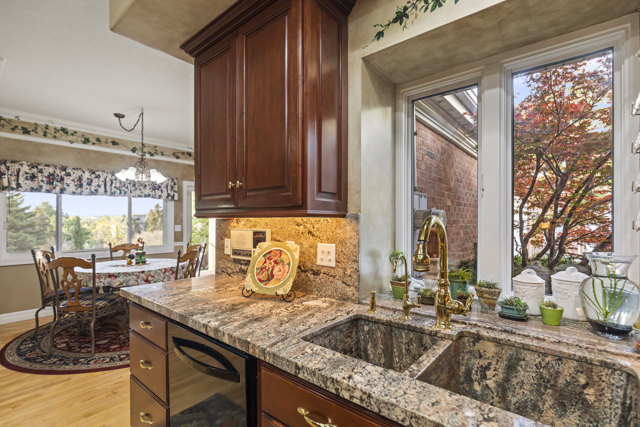 Kitchen featuring backsplash, light wood finished floors, light stone countertops, a chandelier, and crown molding