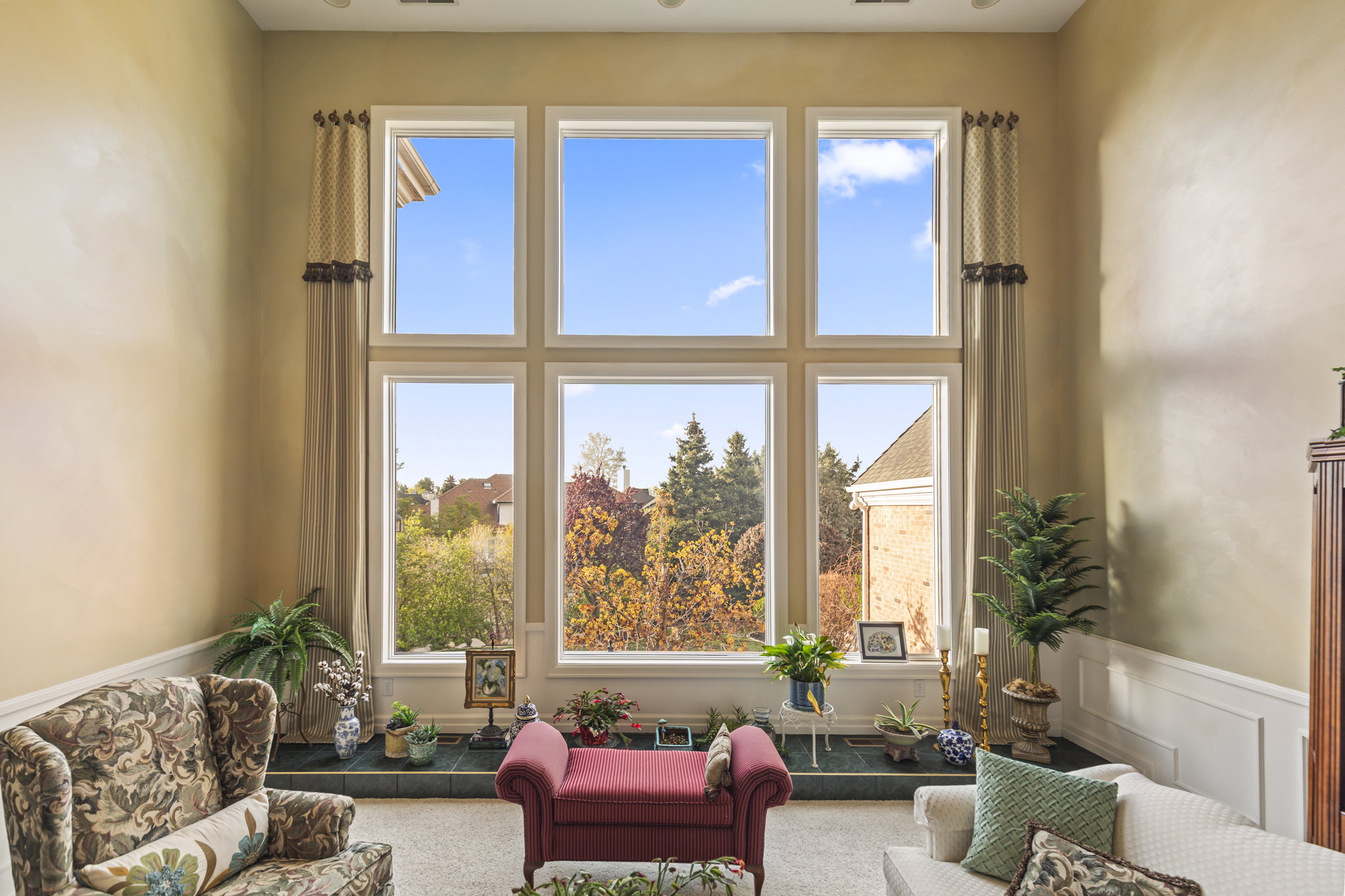Living room with a wainscoted wall, a decorative wall, and a high ceiling