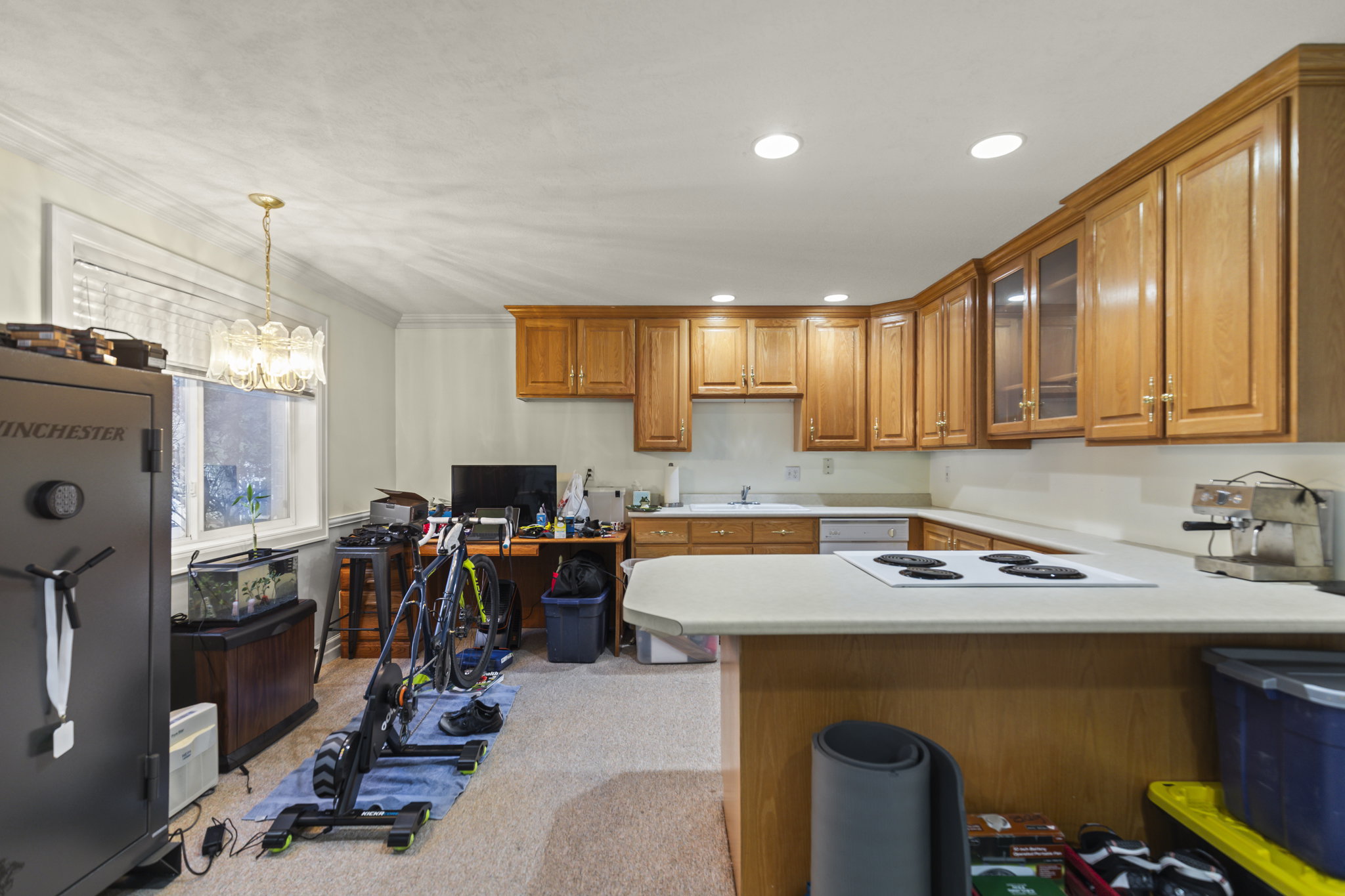 Kitchen featuring wood finish cabinetry, light countertops, a peninsula, a desk, and glass fronted cabinets