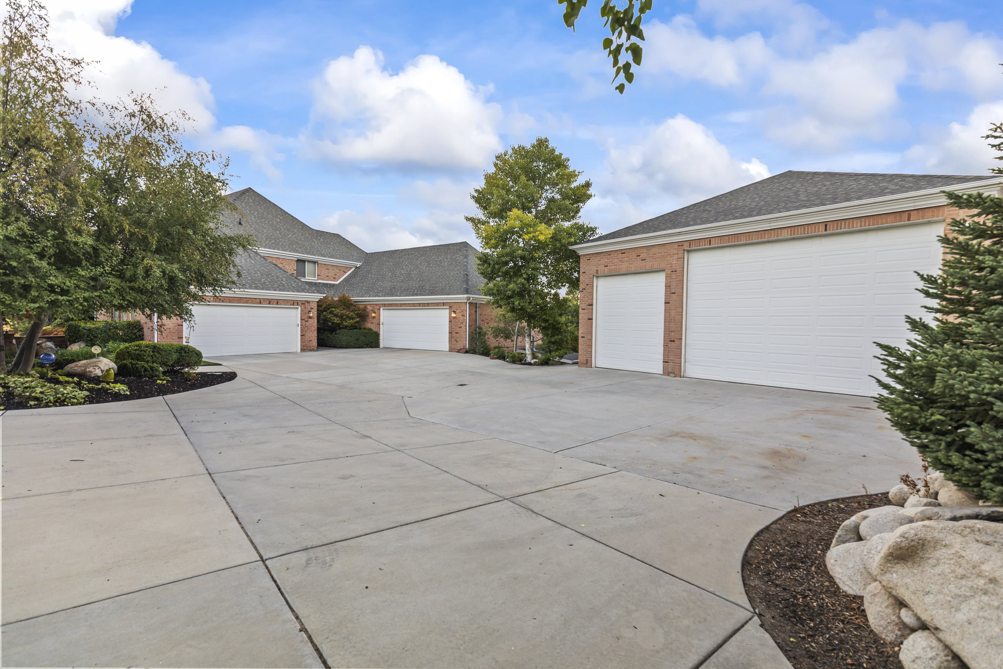 View of front facade with roof with shingles, brick siding, a detached garage, and concrete driveway