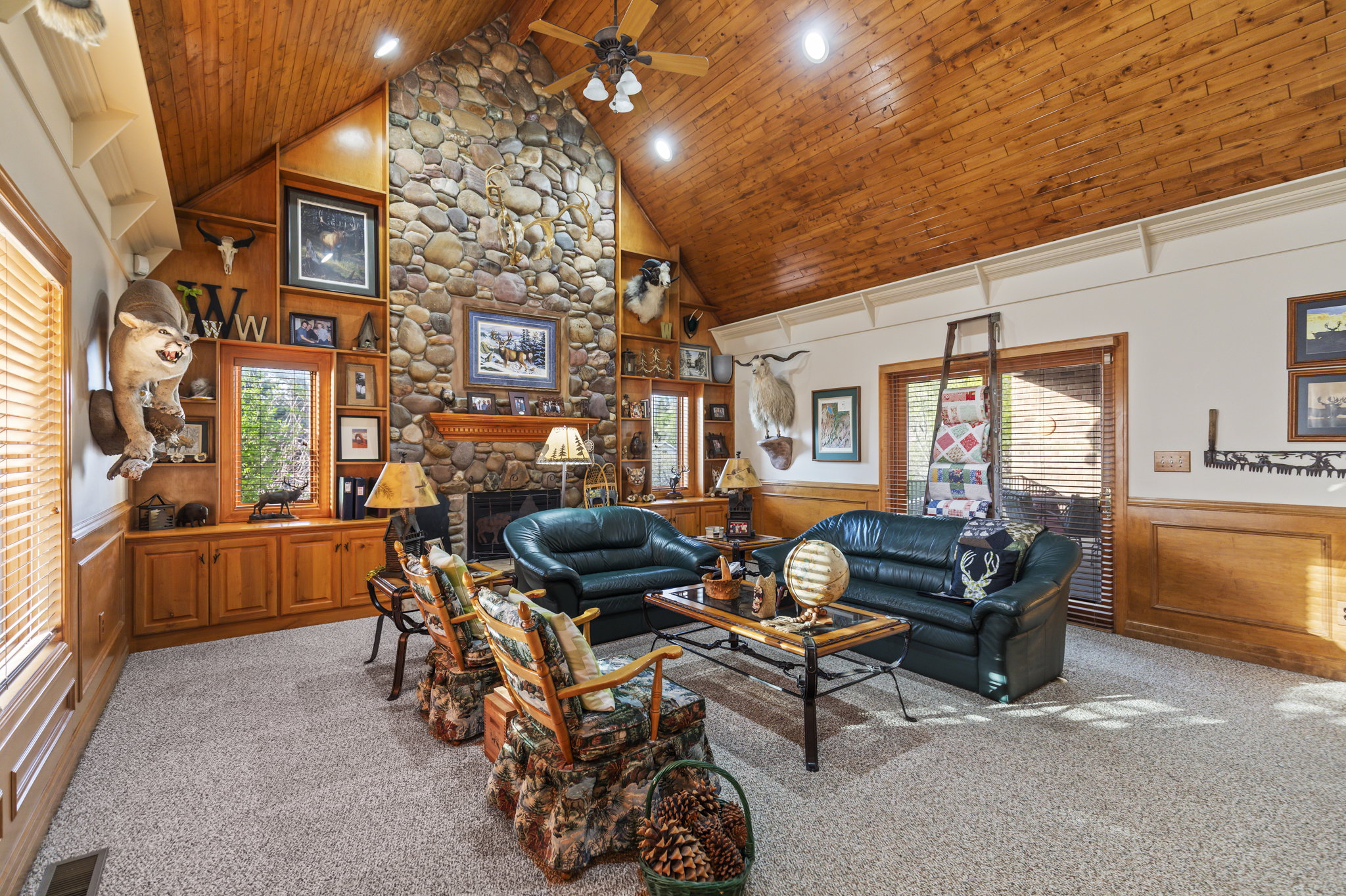 Living area with wainscoting, wood walls, a high wooden ceiling, carpet flooring, and ceiling fan