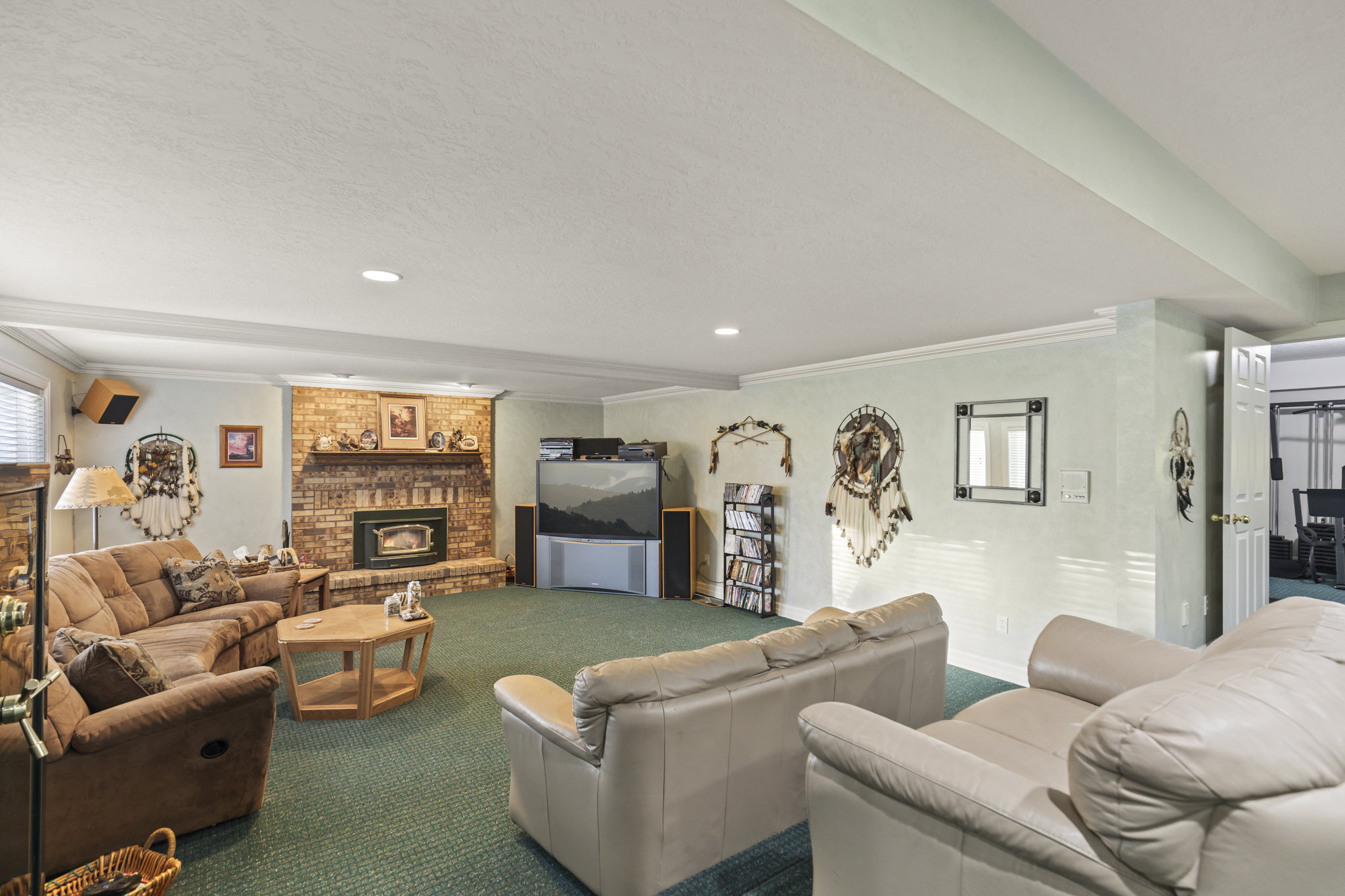 Carpeted living room with ornamental molding, a brick fireplace, plenty of natural light, and recessed lighting
