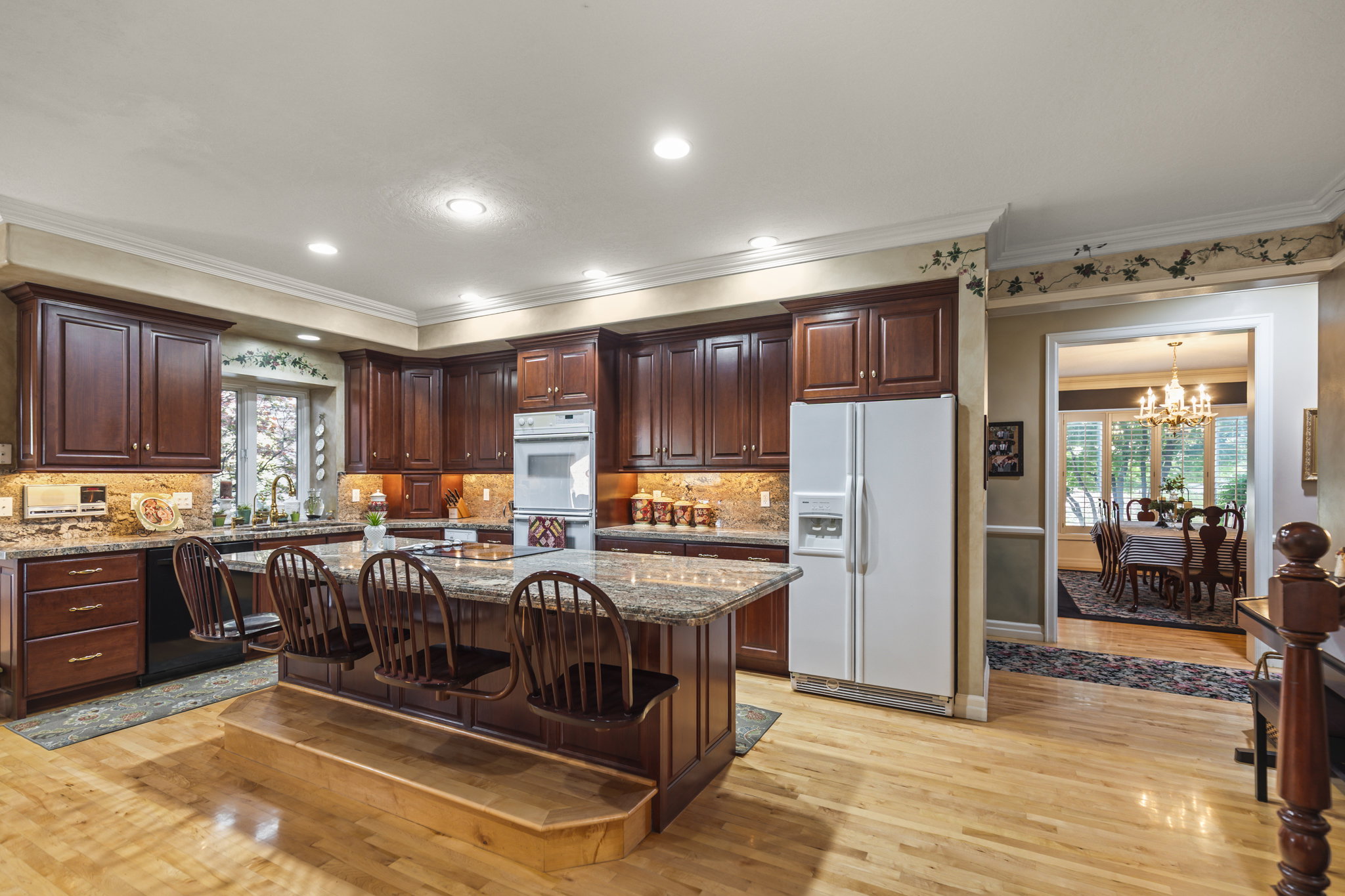 Kitchen with white appliances, light stone counters, a kitchen island, a kitchen bar, and dark wood finish cabinetry