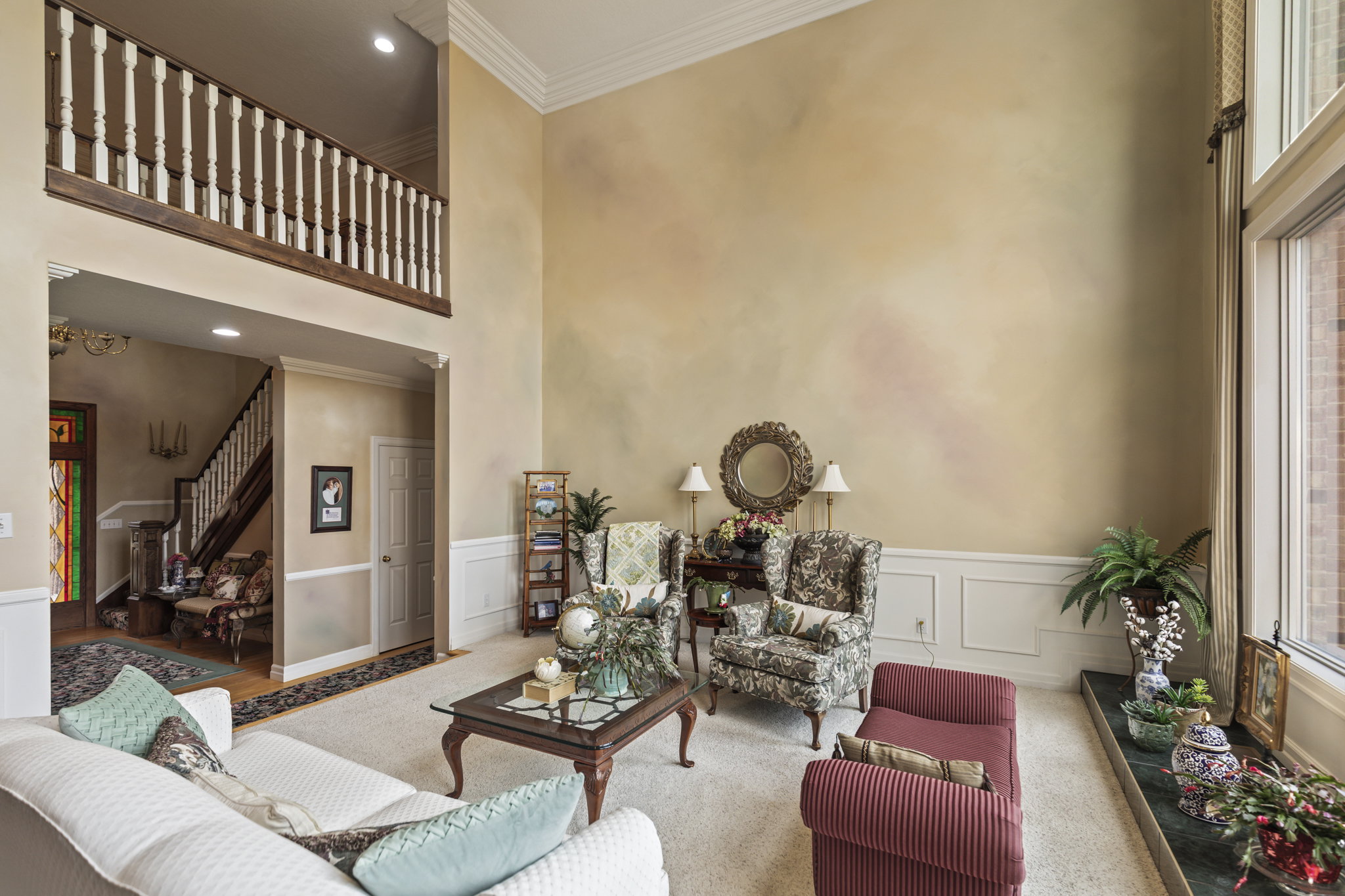Carpeted living room featuring crown molding, a decorative wall, a high ceiling, a wainscoted wall, and recessed lighting