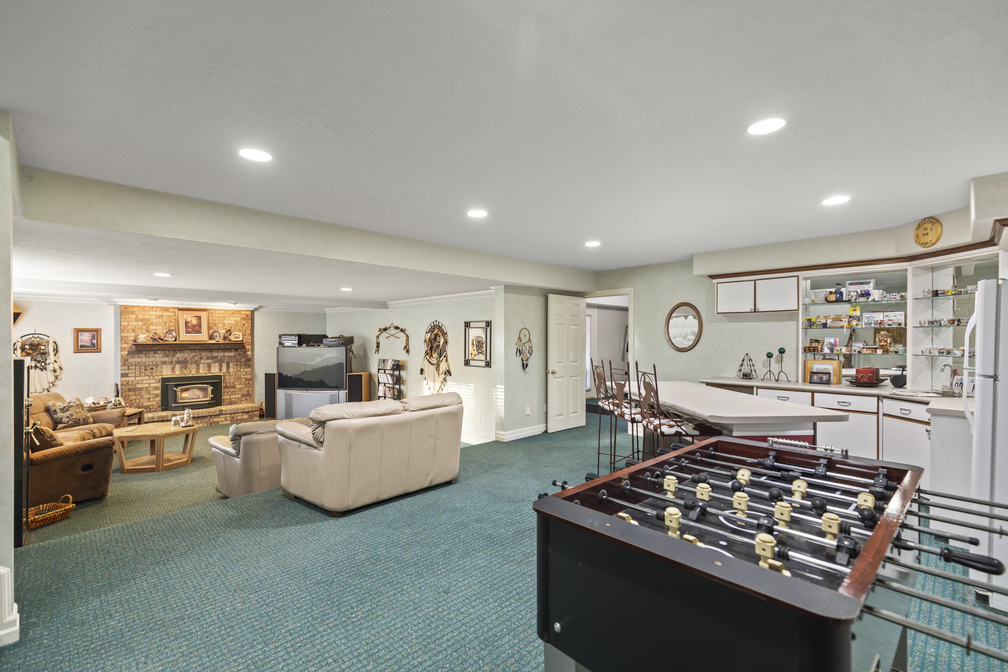 Rec room with dark carpet, a brick fireplace, recessed lighting, and a dry bar