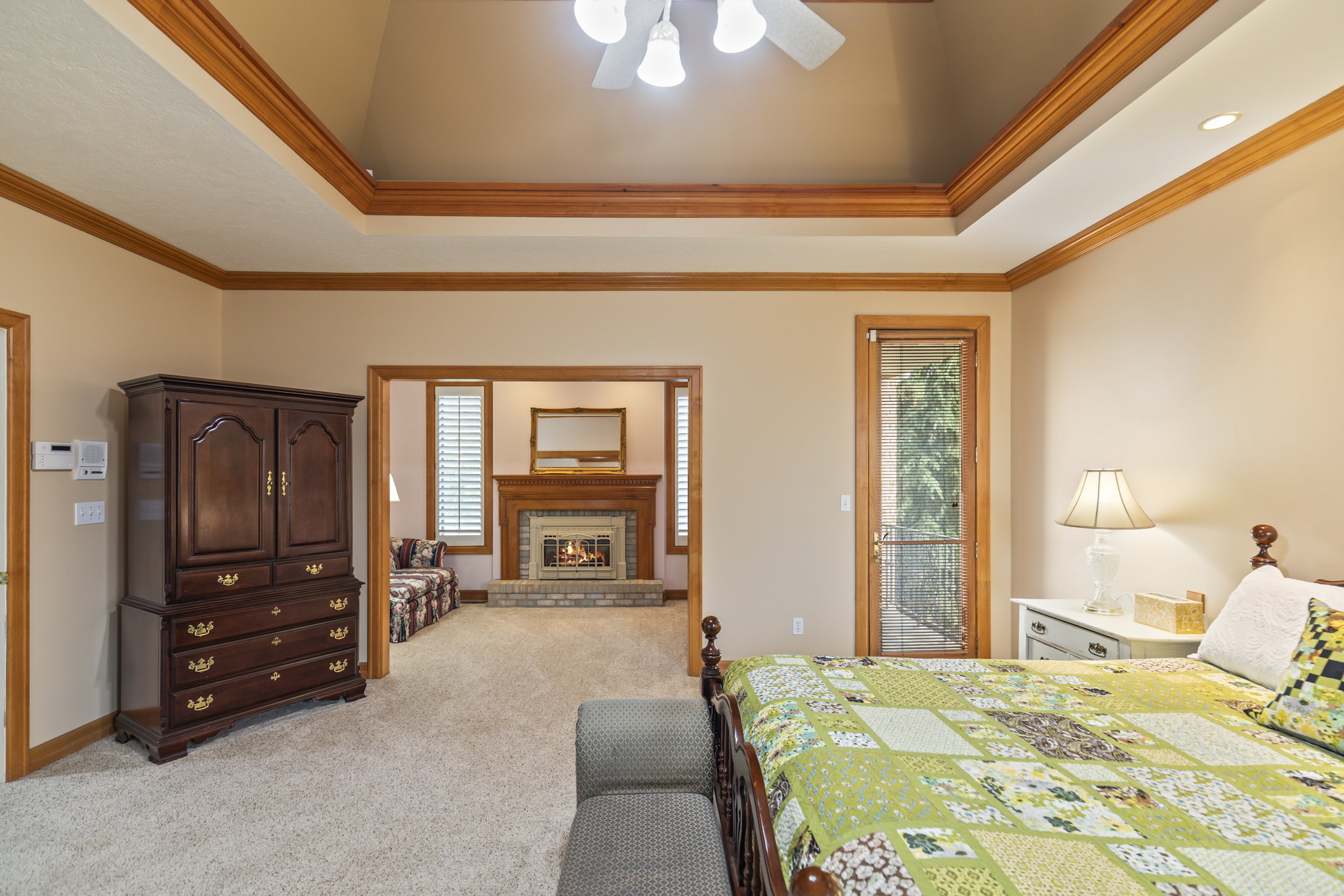 Bedroom with a tray ceiling, access to outside, ornamental molding, a fireplace, and multiple windows