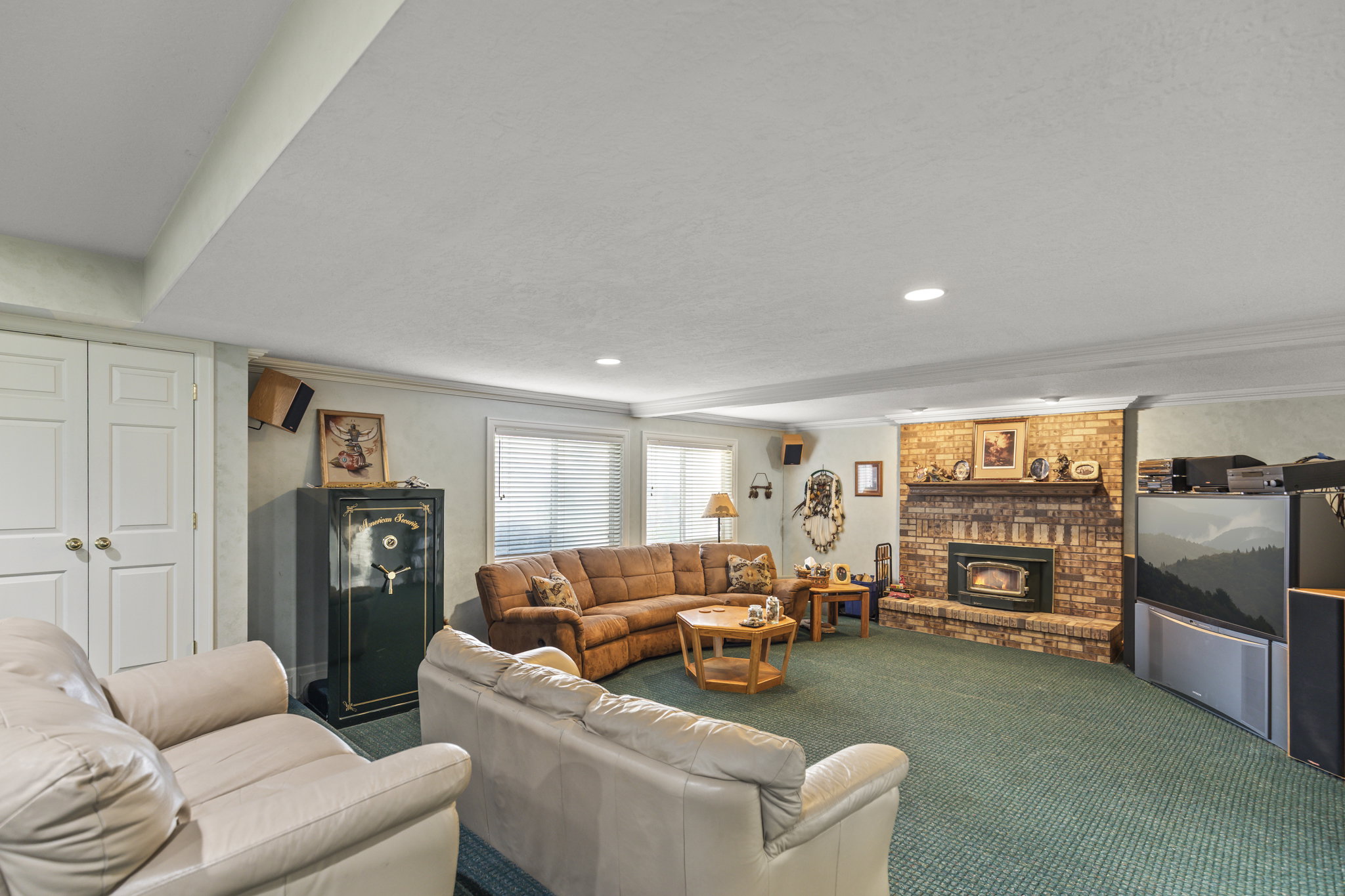 Living room featuring a brick fireplace, crown molding, and carpet floors