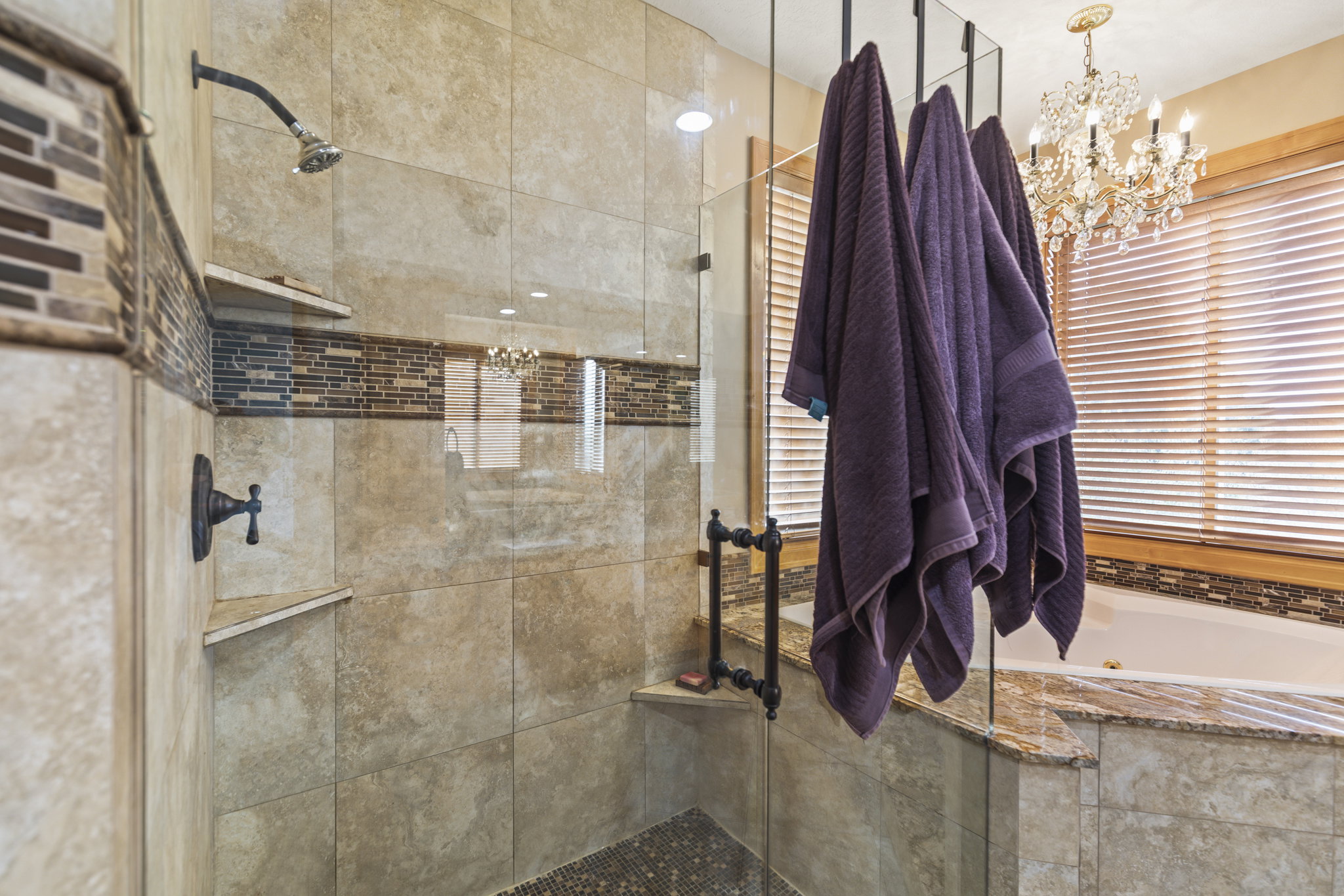 Full bath featuring a shower stall, suspended lighting, a tub with jets, and a towel warming rack