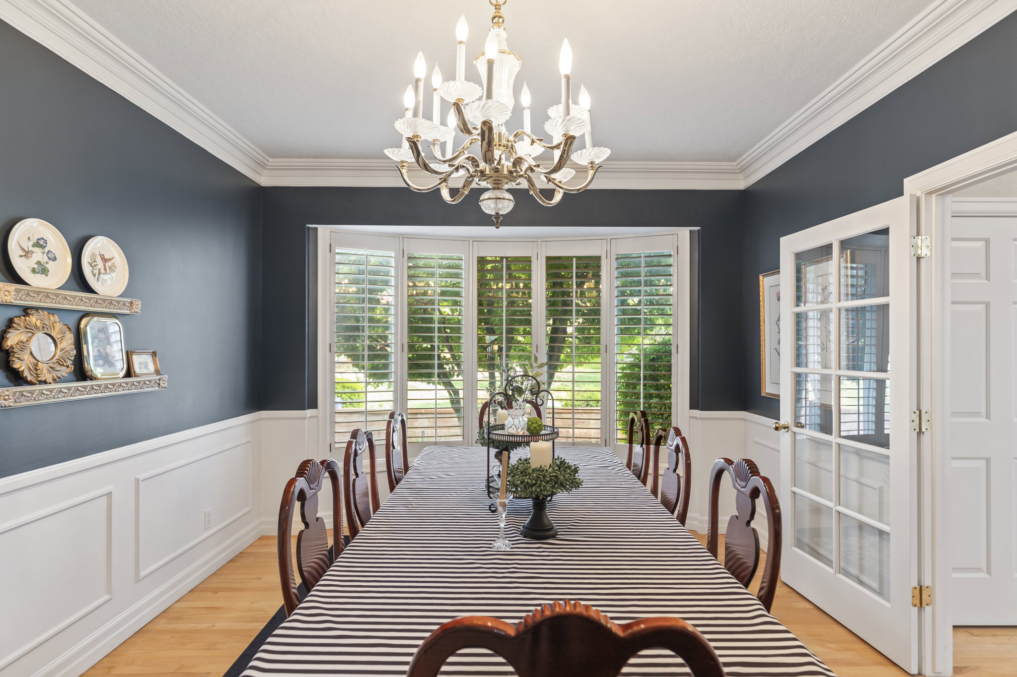 Dining space with plenty of natural light, ornamental molding, light wood-type flooring, wainscoting, and hanging lights