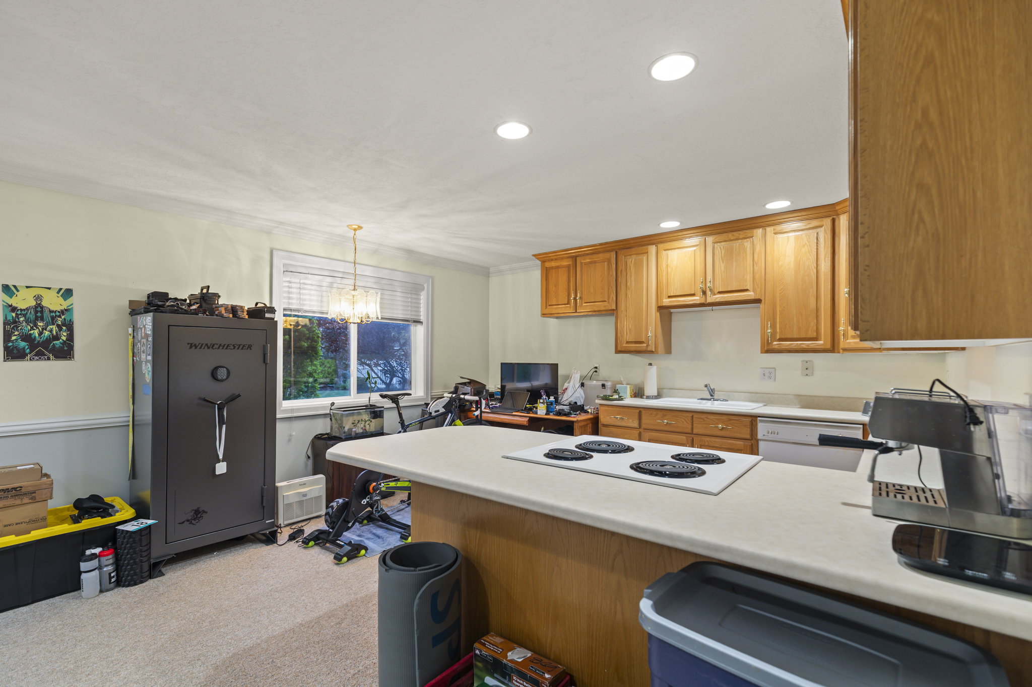 Kitchen featuring light countertops, a peninsula, white appliances, a chandelier, and light colored carpet