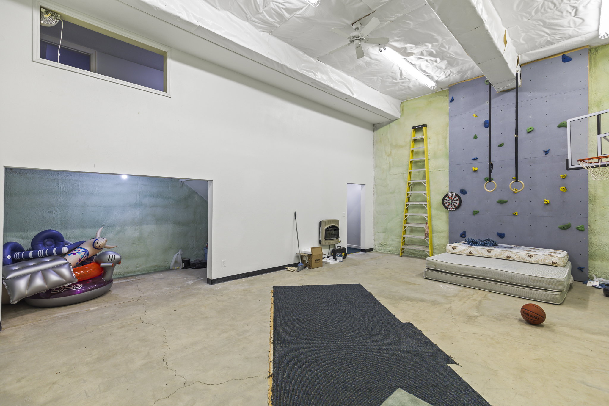 Miscellaneous room with concrete flooring, a high ceiling, and ceiling fan