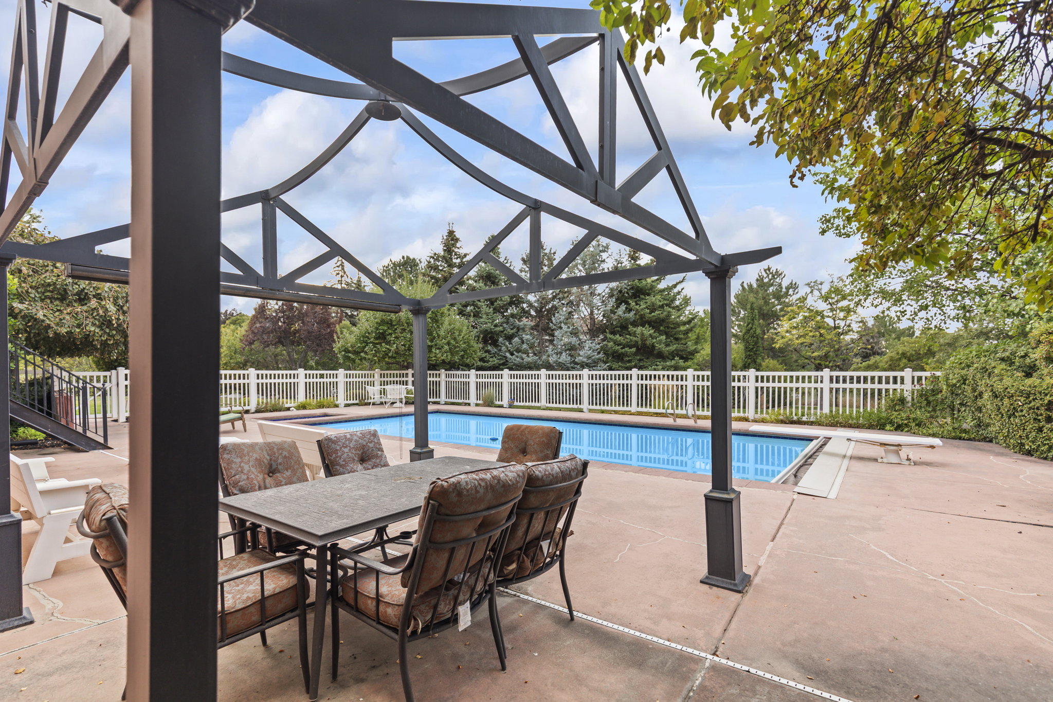 View of swimming pool featuring patio surround, a fenced backyard, a diving board, and outdoor dining space