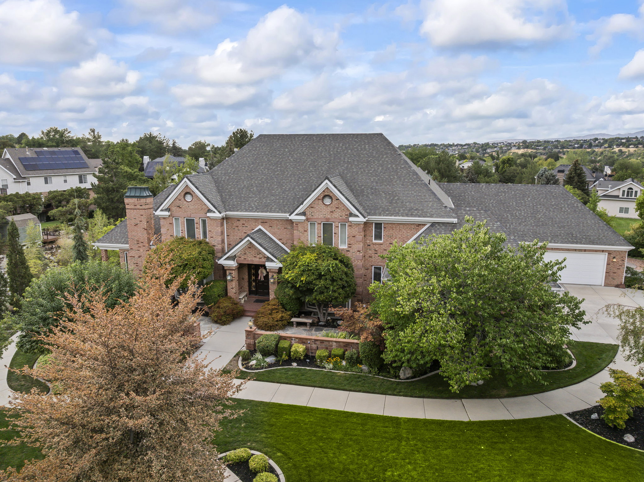 View of front of house with brick siding, a shingled roof, a front yard, concrete driveway, and a residential view