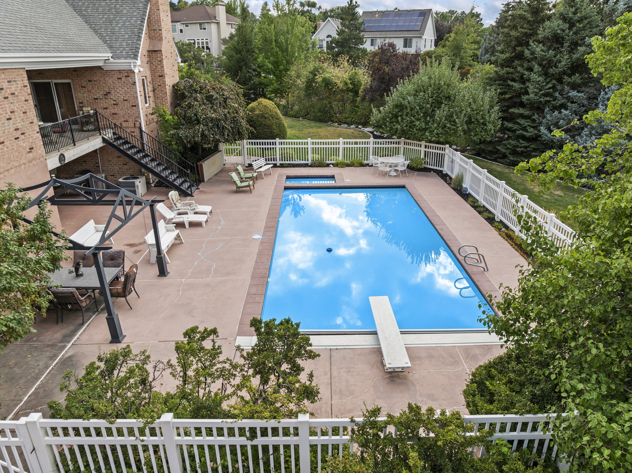 View of pool featuring a fenced backyard, patio surround, a diving board, and view of wooded area