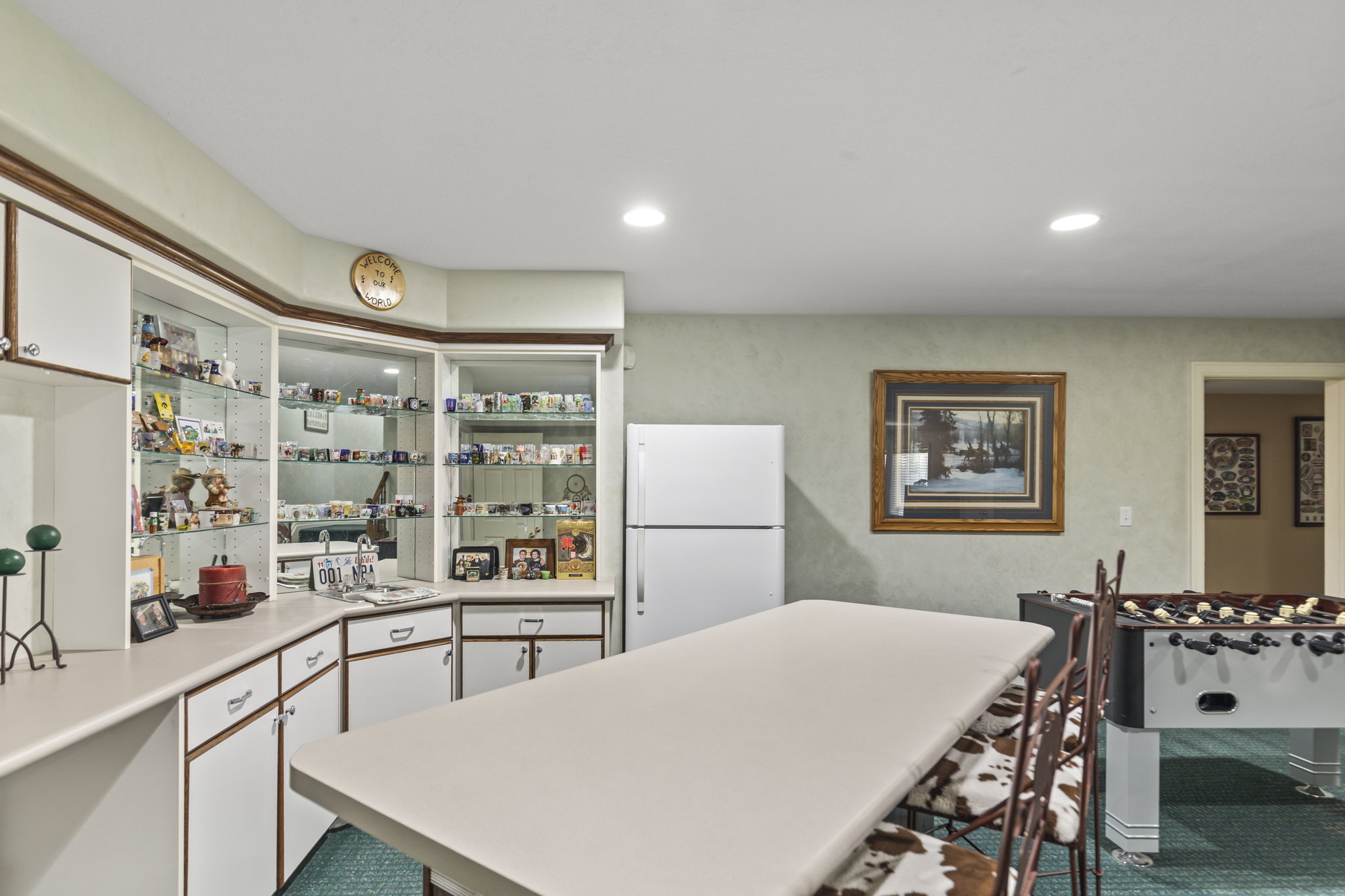 Two tone kitchen with freestanding refrigerator, light countertops, a kitchen breakfast bar, recessed lighting, and a kitchen island