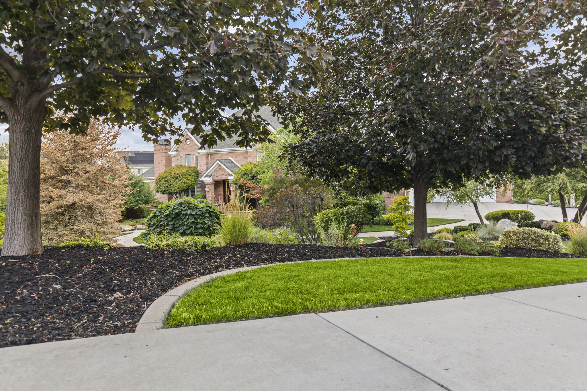 View of property hidden behind natural elements featuring a front yard and brick siding