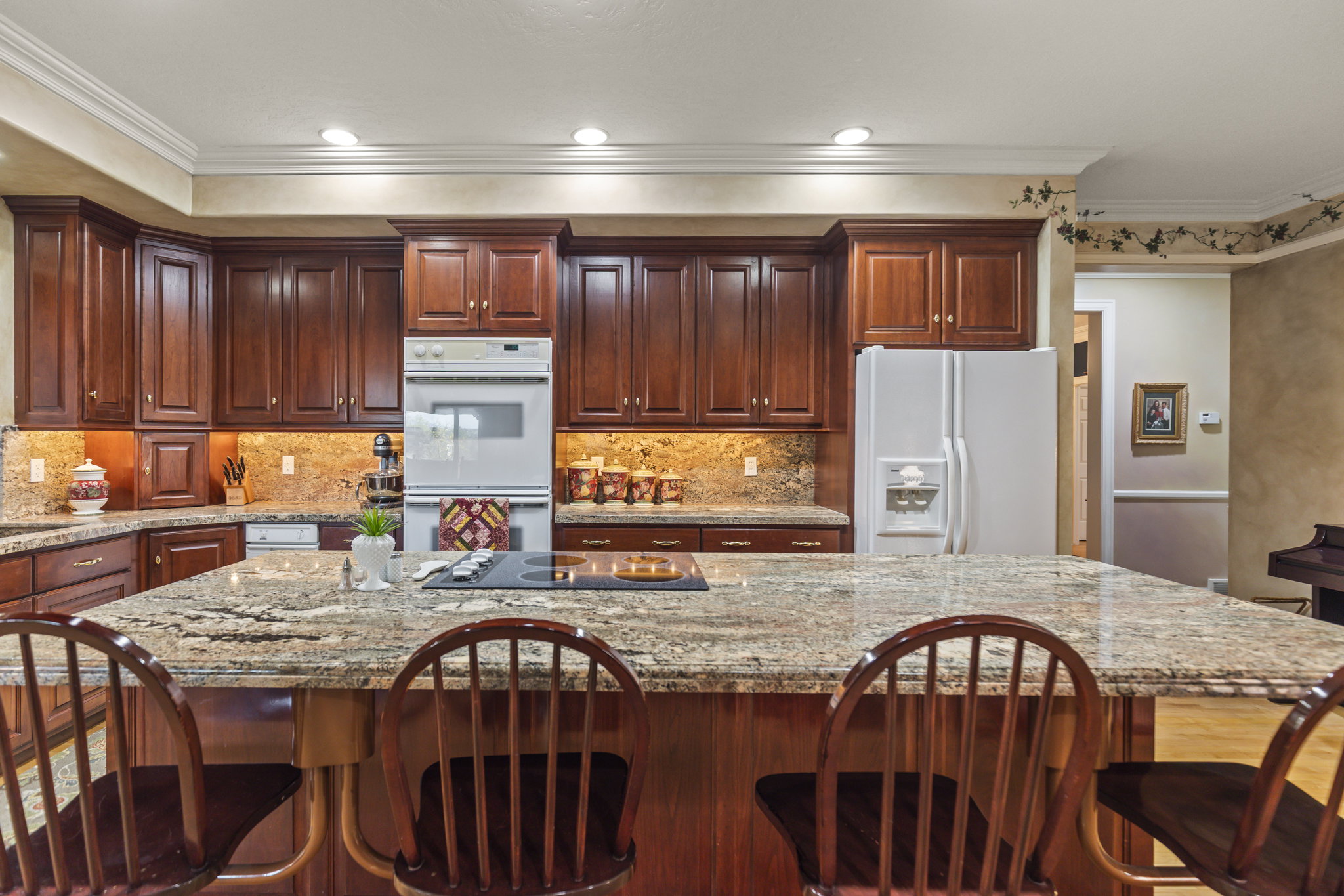 Kitchen with white appliances, light stone counters, a breakfast bar area, ornamental molding, and recessed lighting