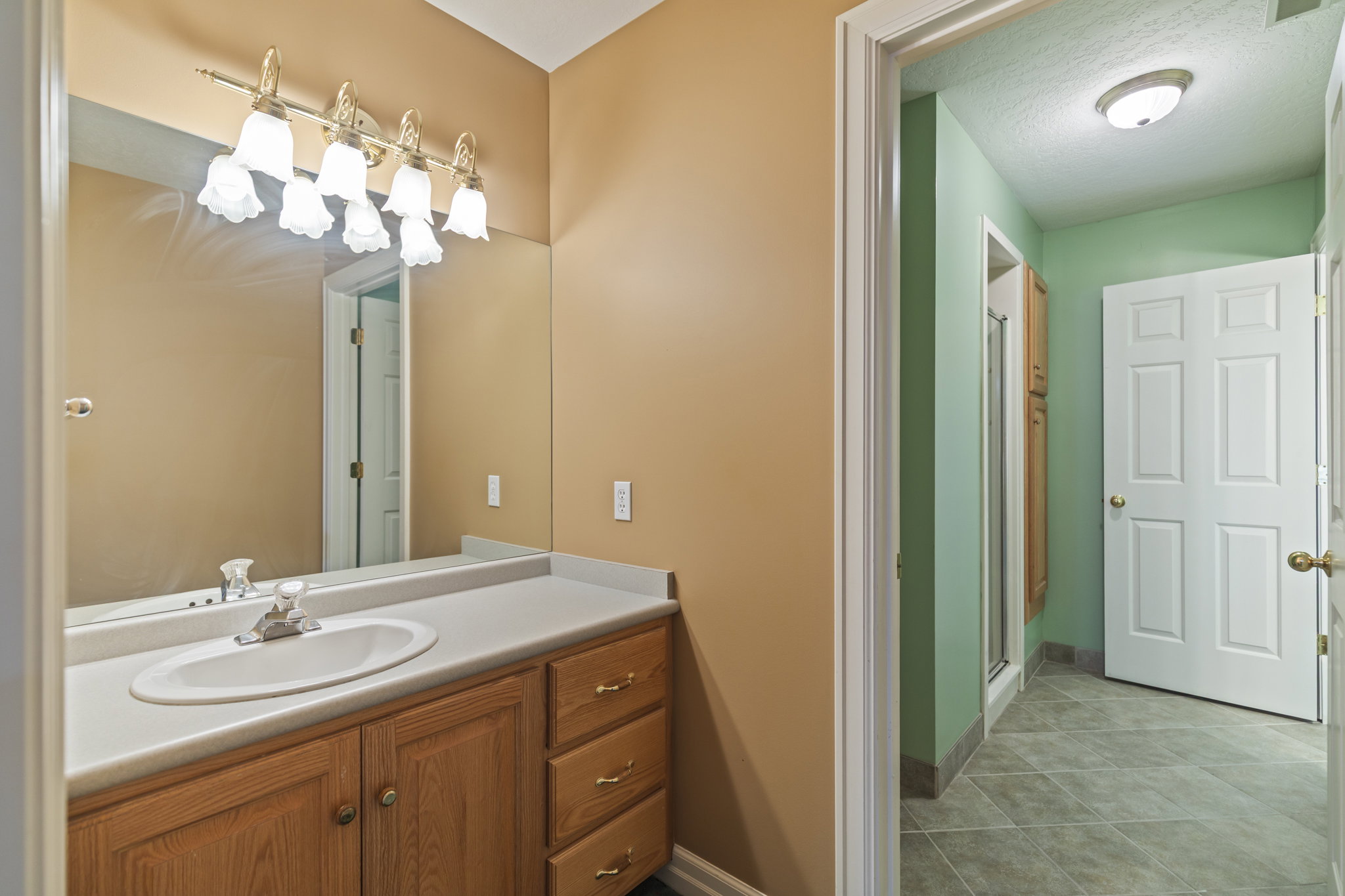 Full bathroom with vanity, a stall shower, light tile patterned floors, and a textured ceiling