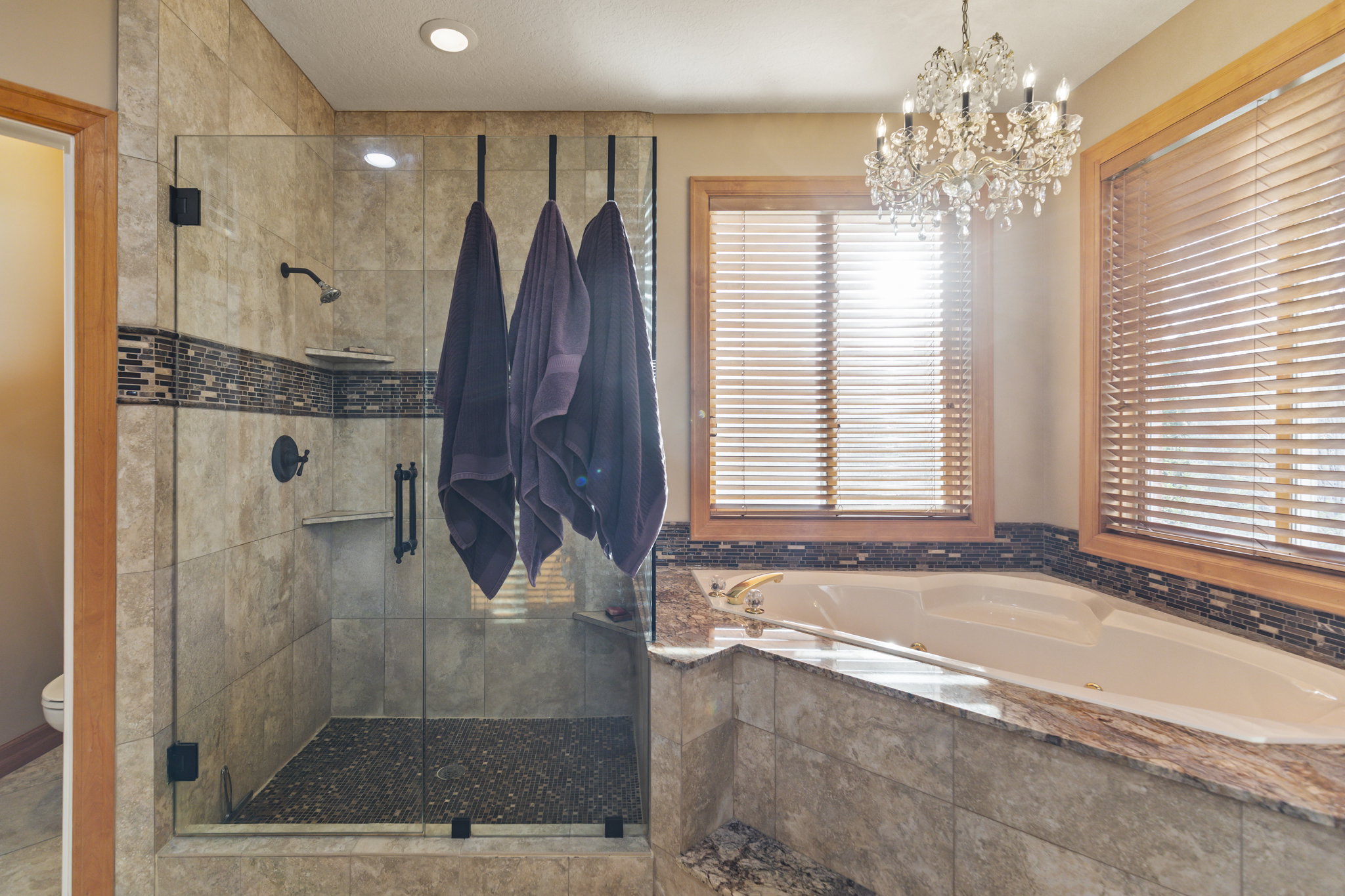 Full bathroom with a stall shower, a jetted tub, and a chandelier