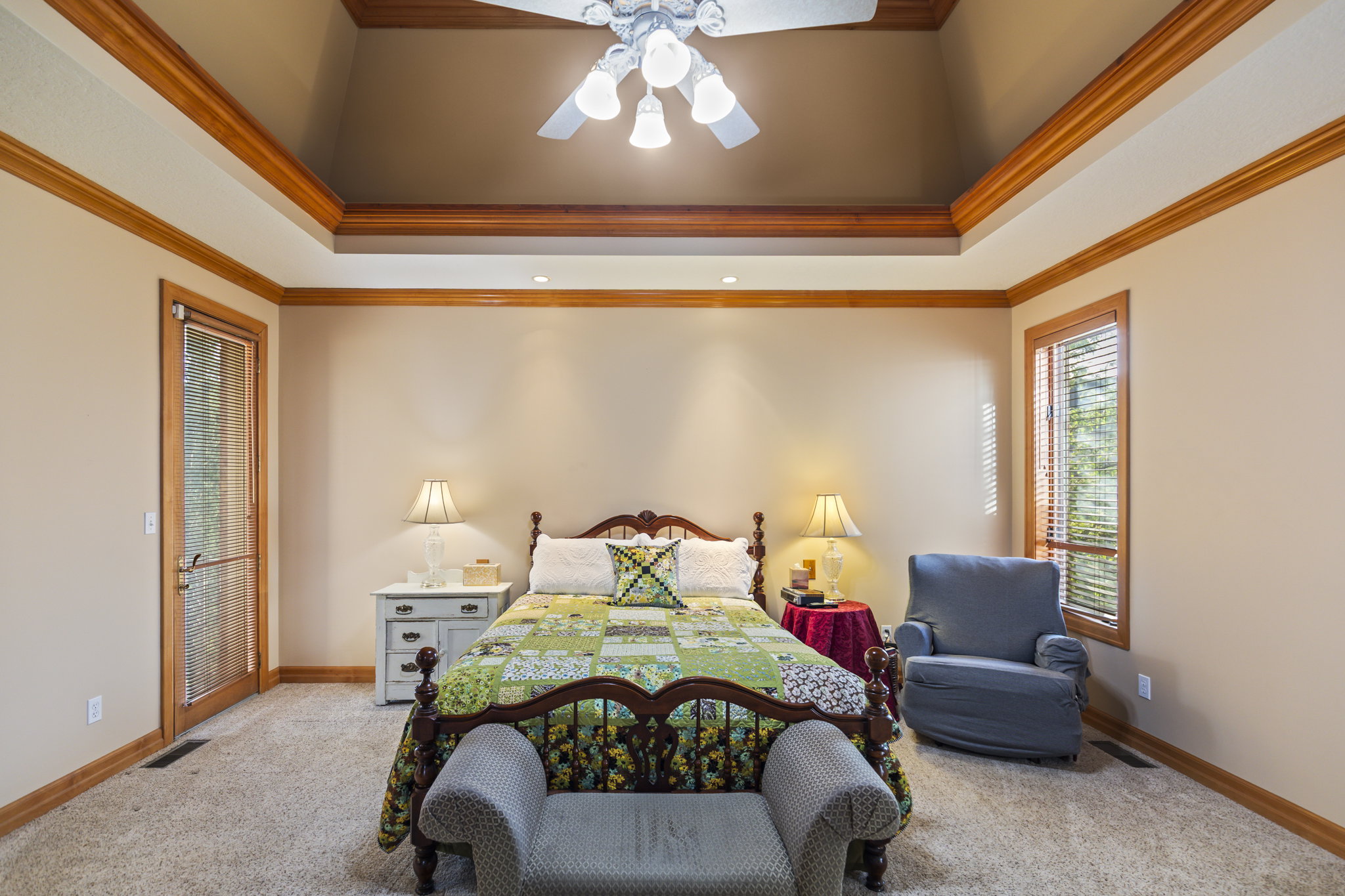 Carpeted bedroom with crown molding, a ceiling fan, a raised ceiling, and suspended lighting