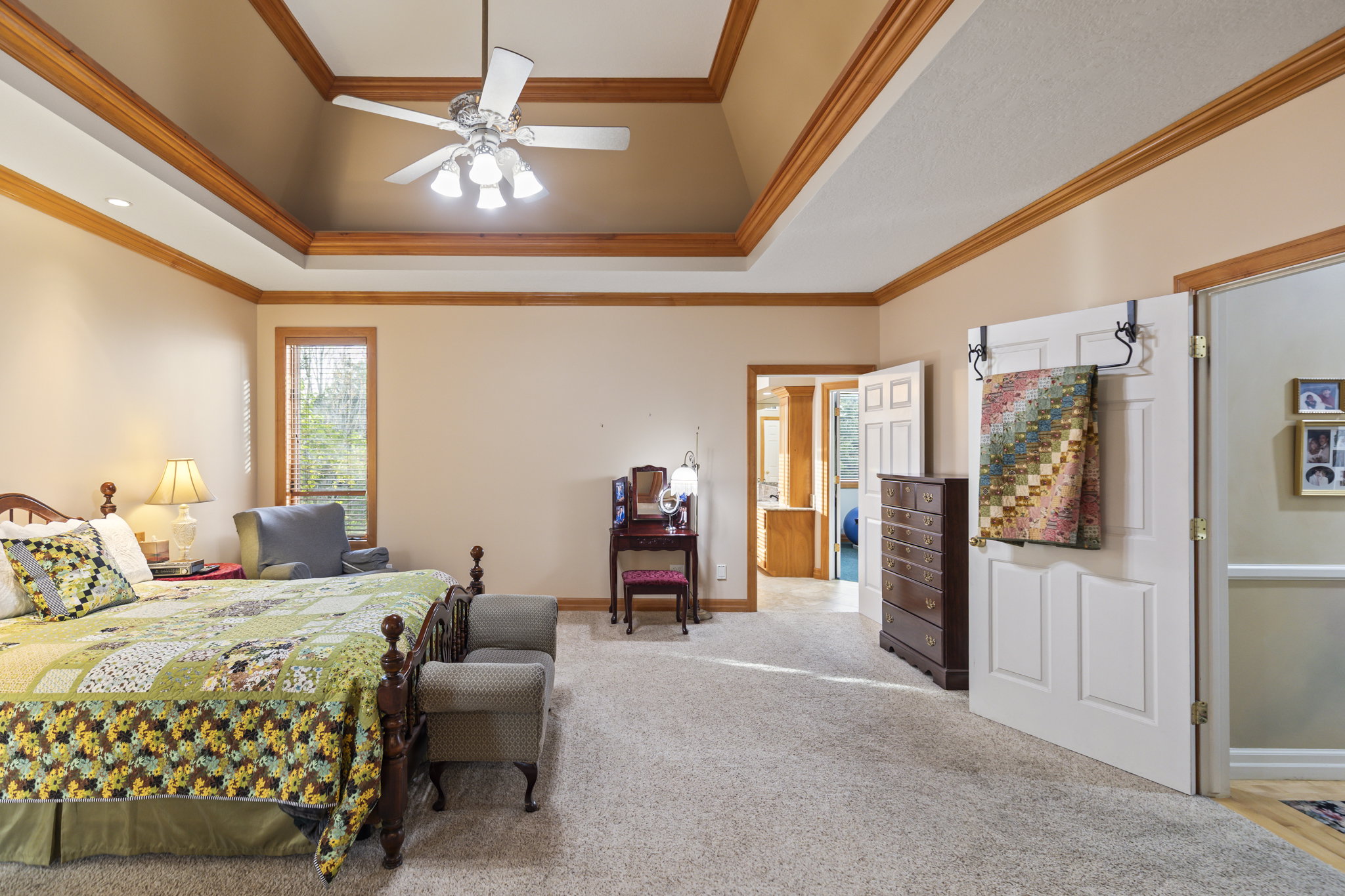 Carpeted bedroom featuring a ceiling fan, ornamental molding, and a raised ceiling
