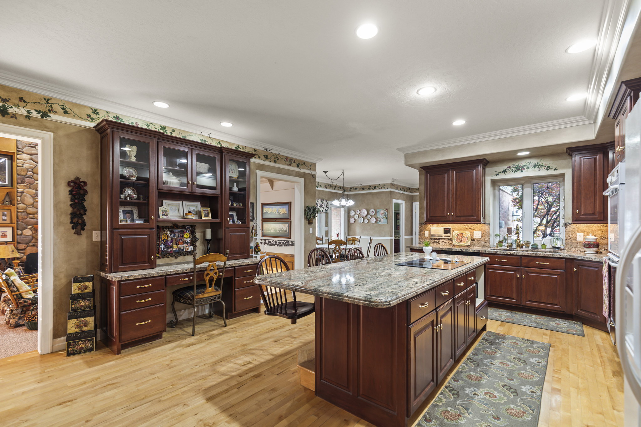Kitchen with crown molding, light wood finished floors, built in desk, a kitchen breakfast bar, and light stone counters