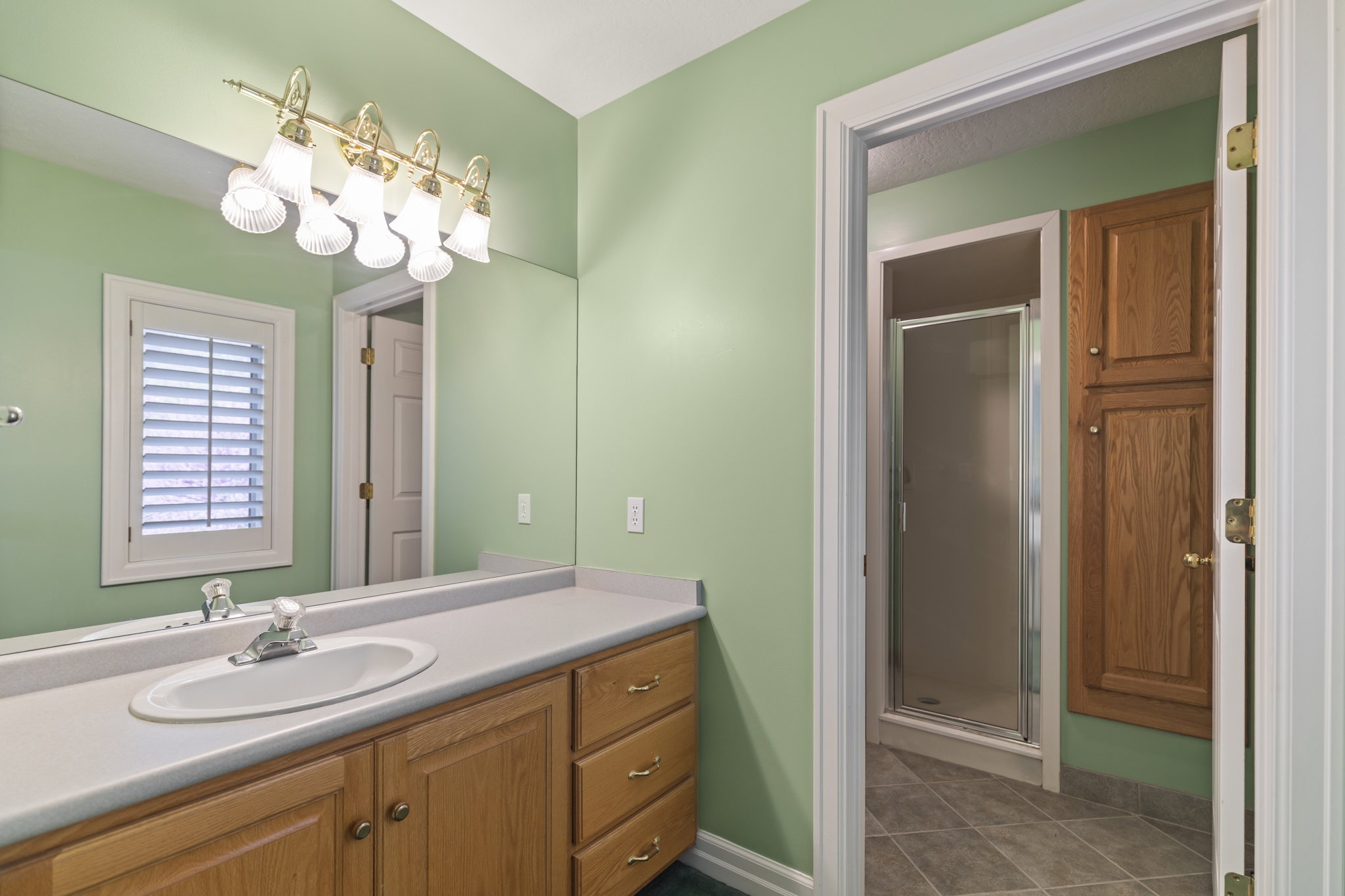 Full bathroom featuring a shower stall, vanity, and dark tile patterned floors