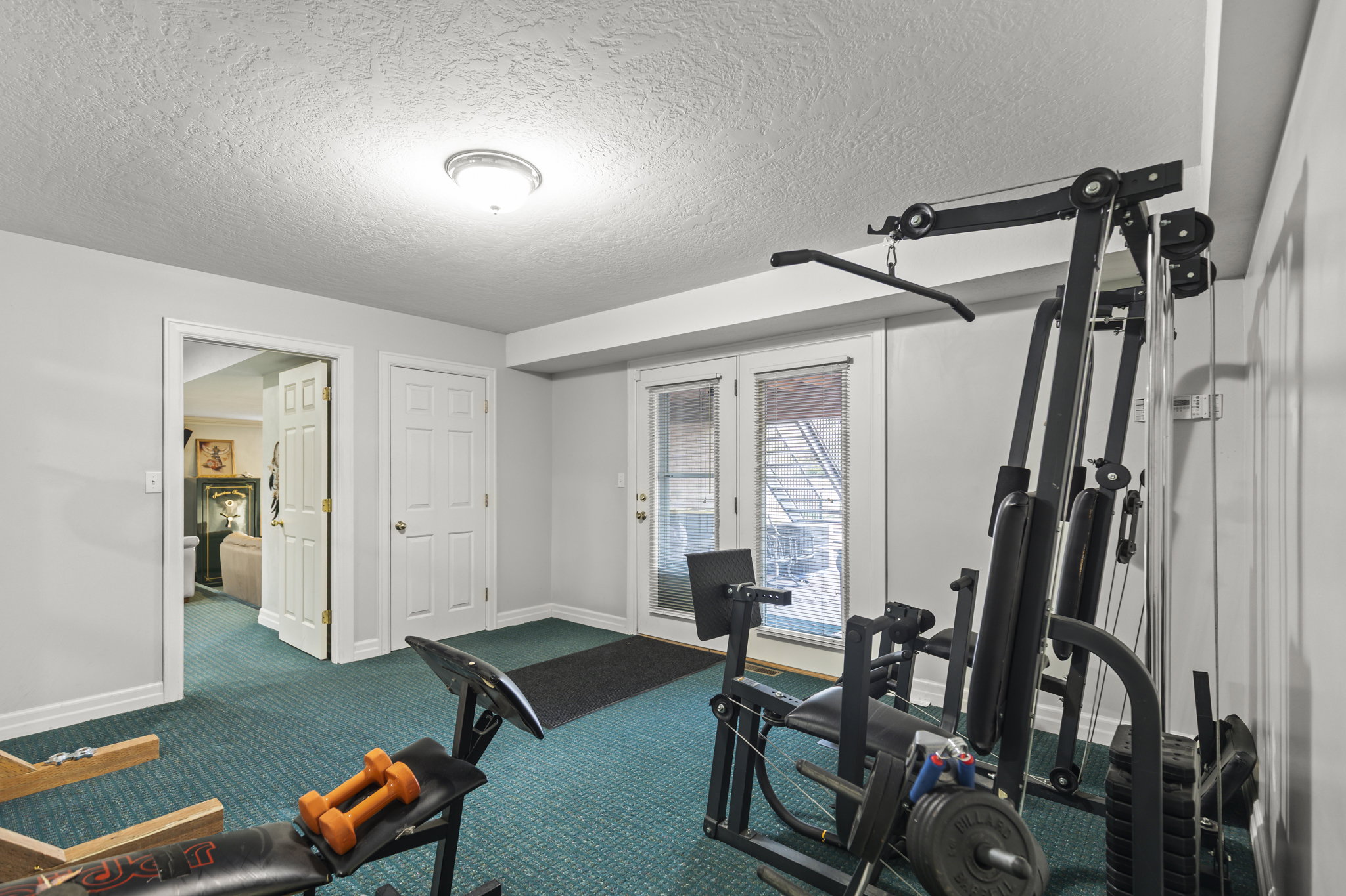 Workout room featuring a textured ceiling and dark colored carpet