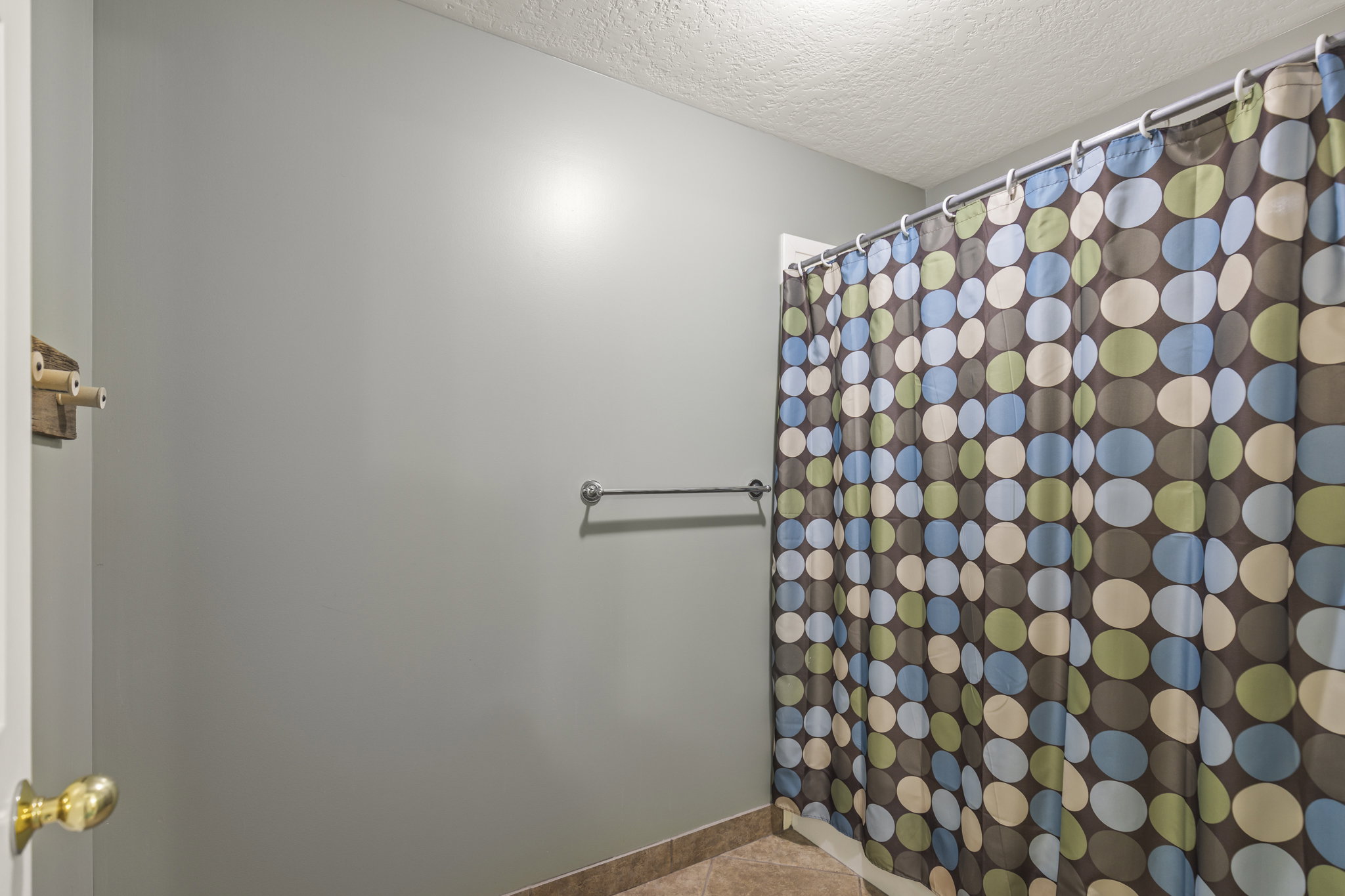 Full bathroom with curtained shower, a textured ceiling, and light tile patterned floors