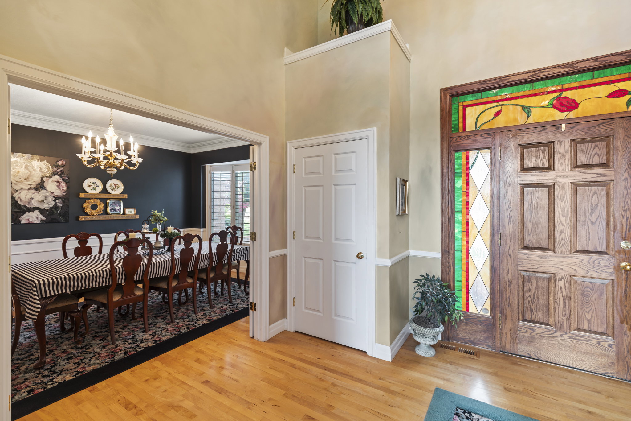 Foyer entrance with a chandelier, light wood finished floors, a high ceiling, and crown molding