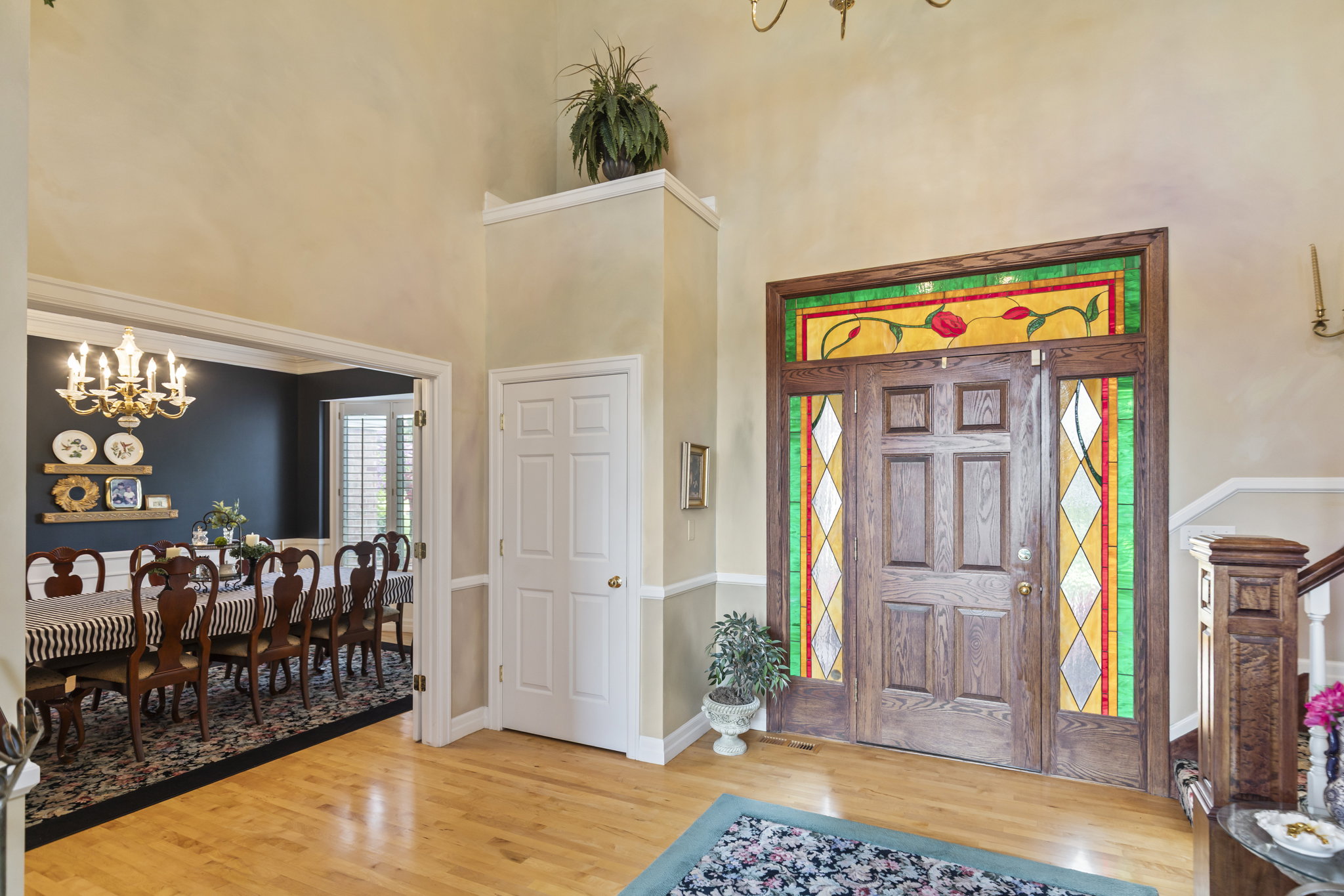 Foyer with suspended lighting, light wood-style flooring, and a high ceiling