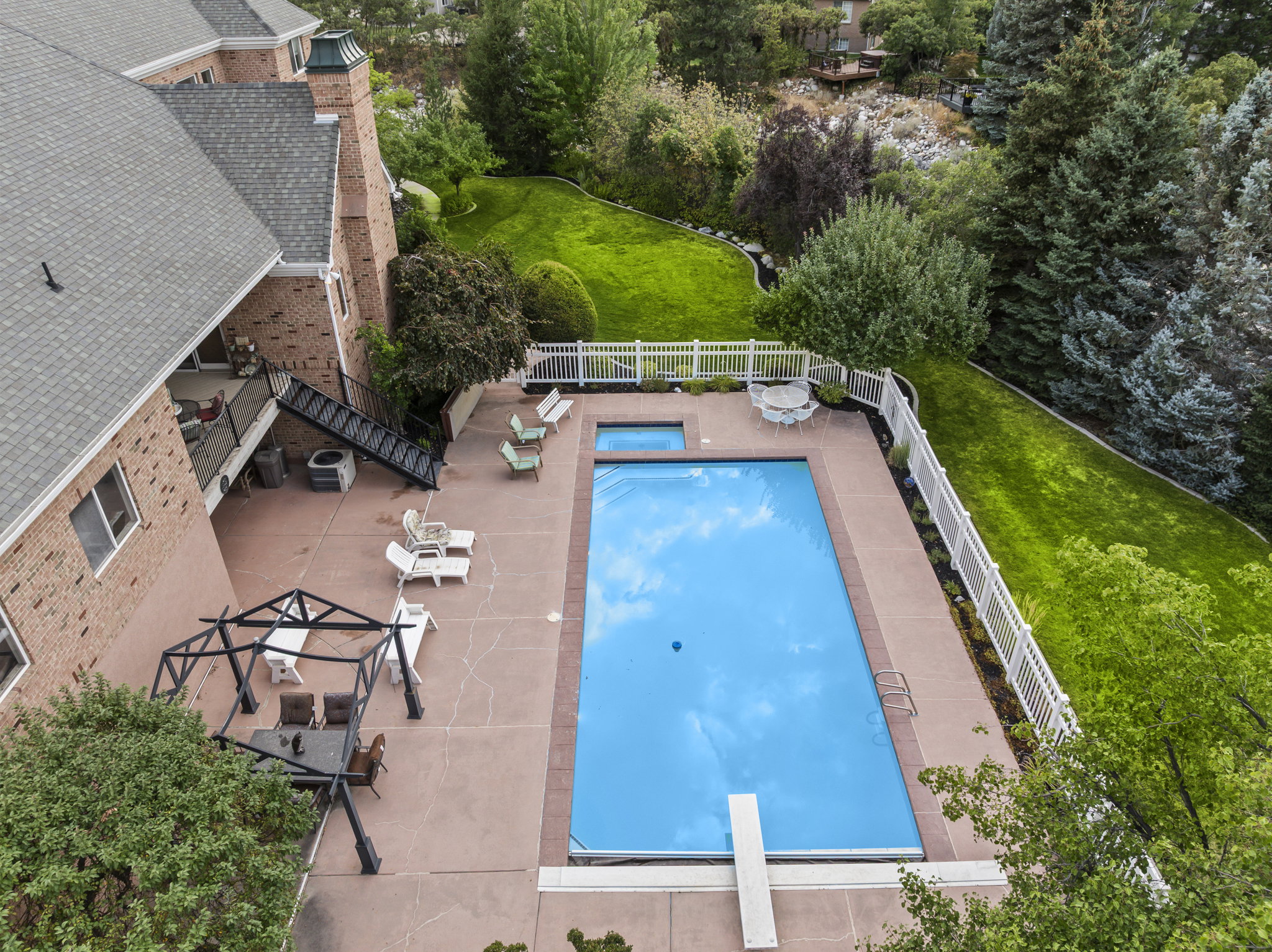 View of swimming pool with patio surround, a fenced backyard, and a diving board