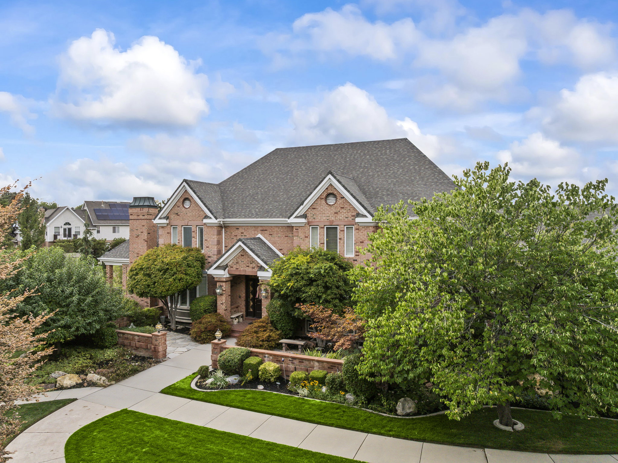 View of front facade with brick siding, roof with shingles, and a front yard