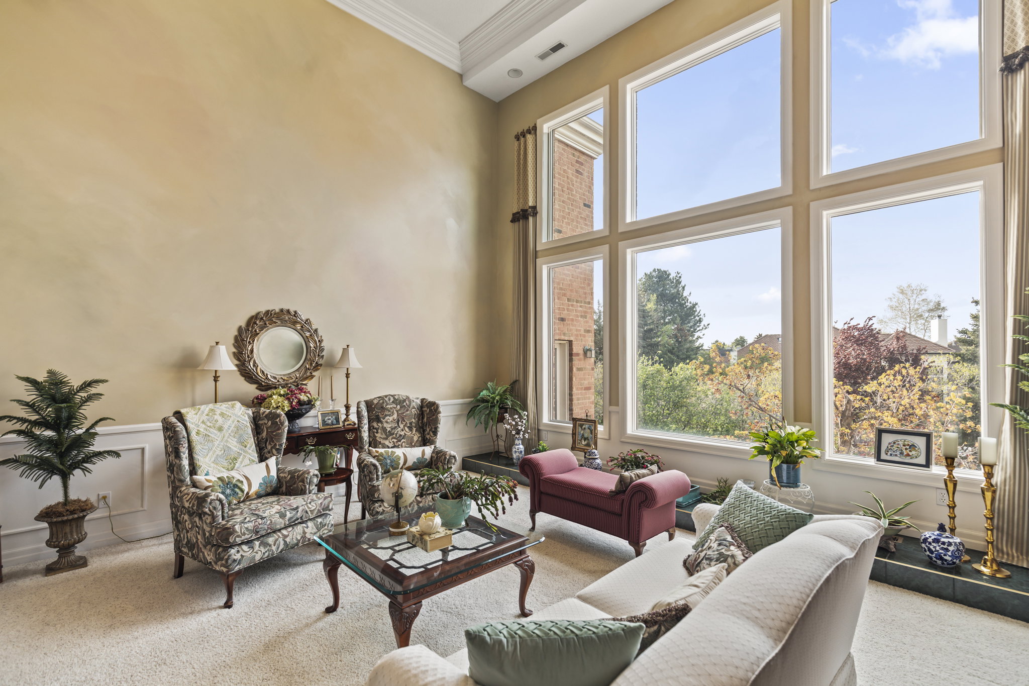 Living room with ornamental molding, carpet, a decorative wall, wainscoting, and a high ceiling