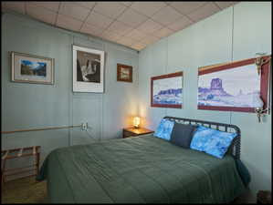 Bedroom featuring light blue paneled walls, and carpeted flooring