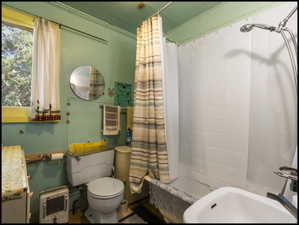 Bathroom featuring a window, white fixtures, and a shower/tub combination