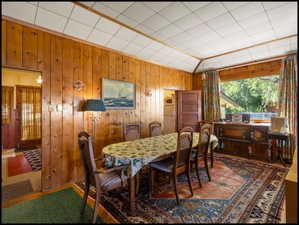 Room featuring wood paneling on walls, a drop ceiling, and a large window with exterior greenery