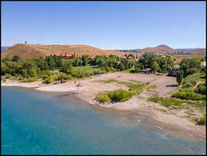 Expansive waterfront property featuring a tranquil lake, private beach area, and surrounding natural landscape