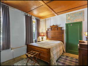 Room featuring wood-finish ceiling, light-colored walls, and windows with drapery
