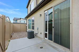 Exterior concrete patio with a full-height privacy fence and an adjacent gravel area