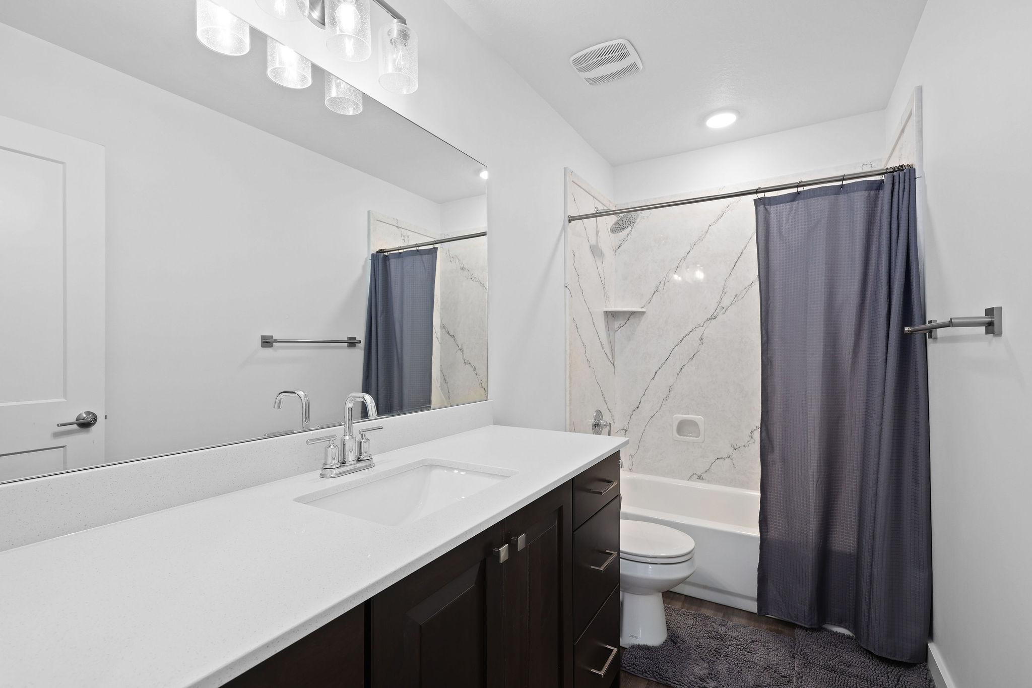 Bathroom featuring a white vanity with an integrated sink, dark wood-finish cabinetry, and a large wall-mounted mirror