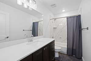 Bathroom featuring a white vanity with an integrated sink, dark wood-finish cabinetry, and a large wall-mounted mirror